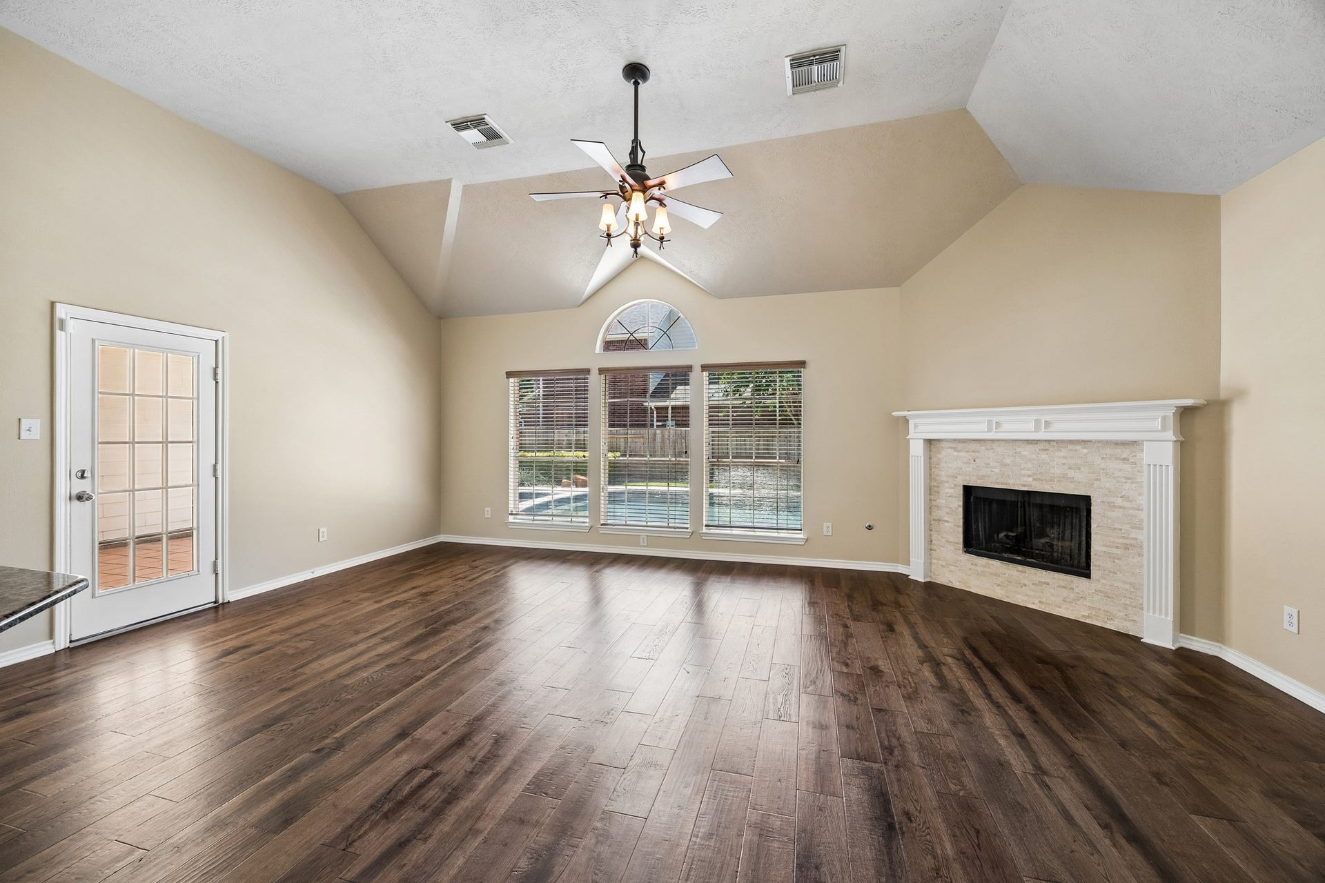 Spacious family room featuring soaring ceilings, engineered hardwood flooring, a cozy fireplace, built-in cabinetry, and abundant natural light. The open layout offers plenty of room for gathering, entertaining, and everyday living.