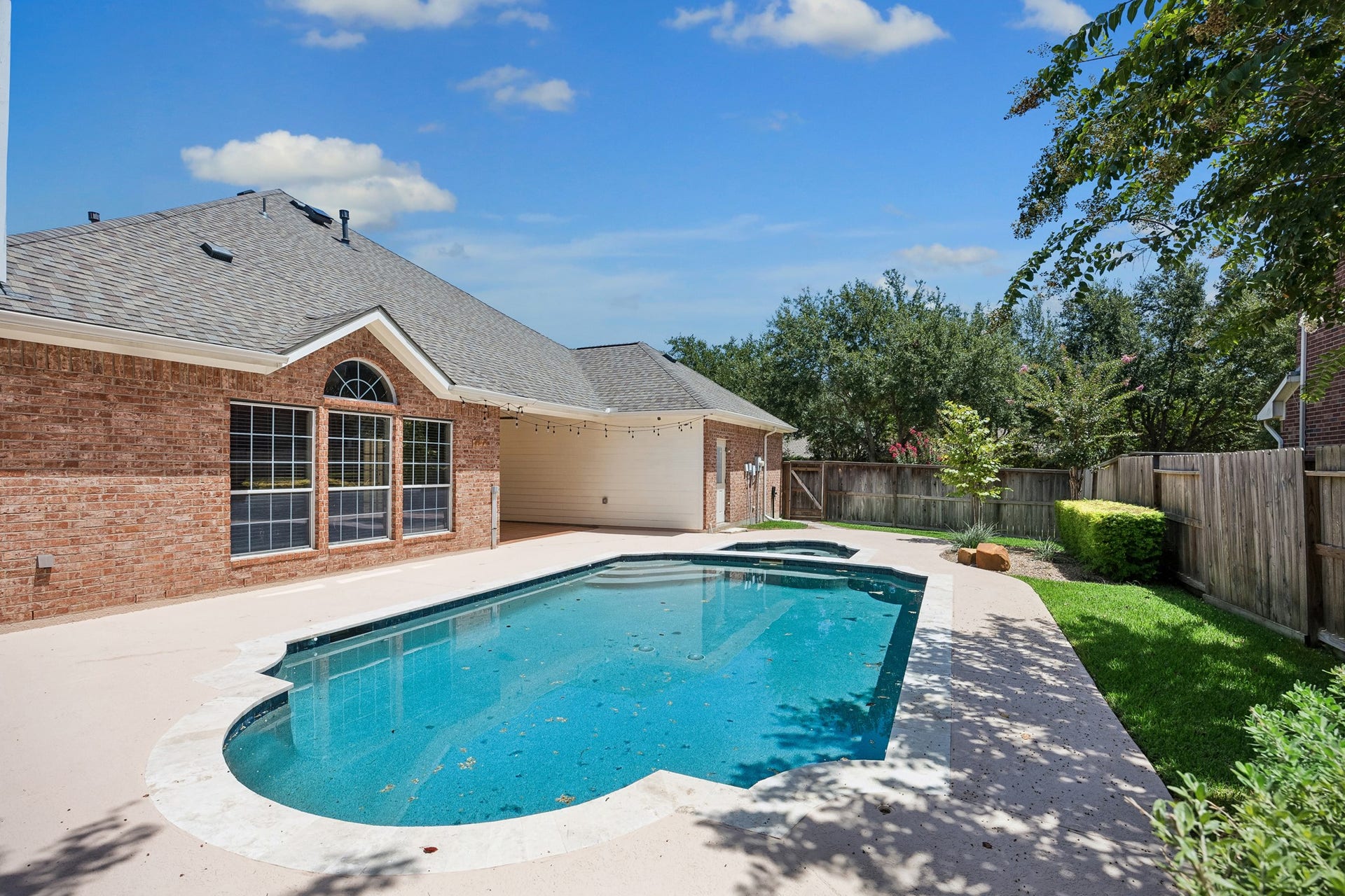 Another view of the private backyard oasis highlights the sparkling updated pool, generous poolside space, mature landscaping, and added privacy, creating an ideal setting for outdoor entertaining, relaxing, and enjoying sunny Texas days.