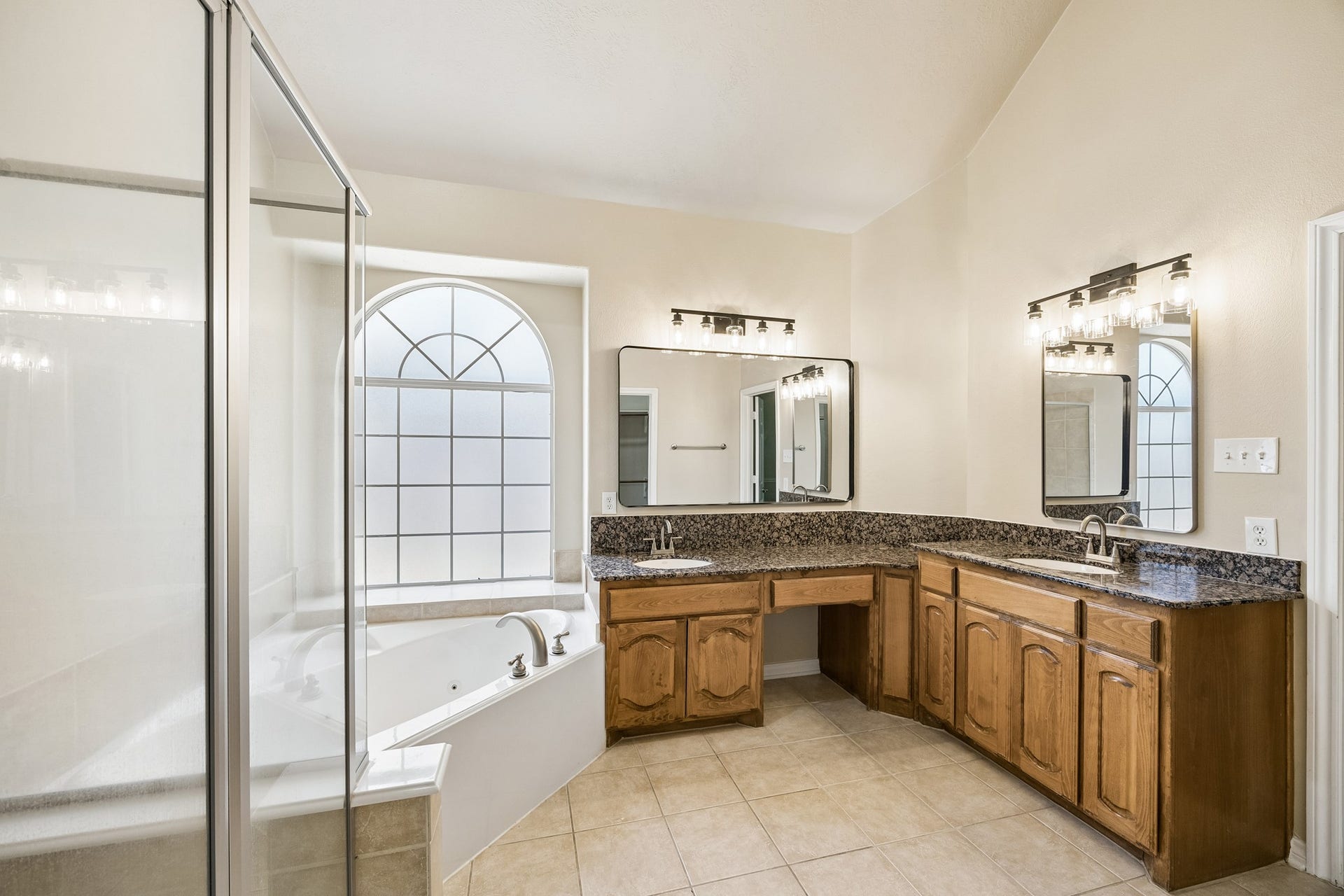 Another view of the primary bath highlights the expansive dual vanity, abundant cabinetry, separate glass-enclosed shower, and large window bringing in natural light, offering plenty of space for comfortable everyday routines.