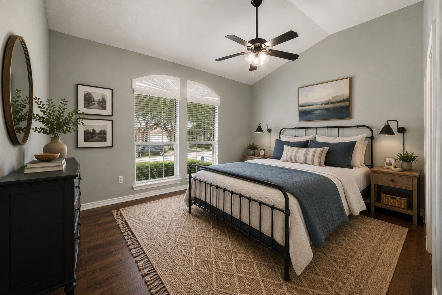 Virtually staged secondary bedroom features a beautiful arched window that adds architectural character and natural light, along with engineered hardwood flooring, a ceiling fan, and generous space for a complete bedroom suite.