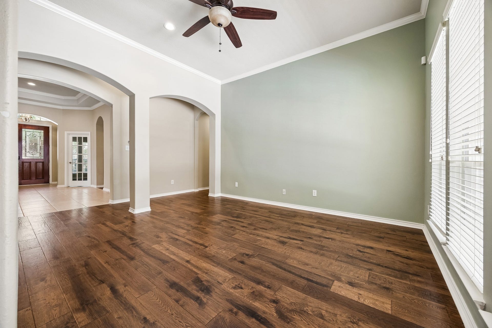 Secondary sitting area offers a flexible space for relaxing, reading, or conversation, featuring engineered hardwood flooring, high ceilings, graceful arched openings, and an open connection to the surrounding living spaces.