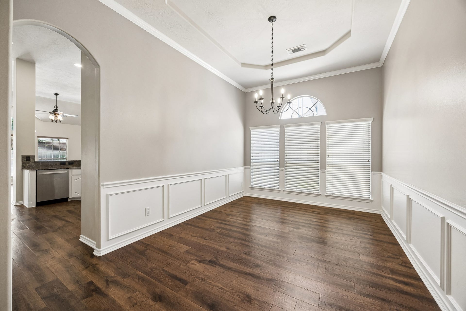 Formal dining room offers generous space for a large dining table and gatherings, with engineered hardwood flooring, elegant trim details, updated lighting, and easy access to the kitchen for effortless entertaining.