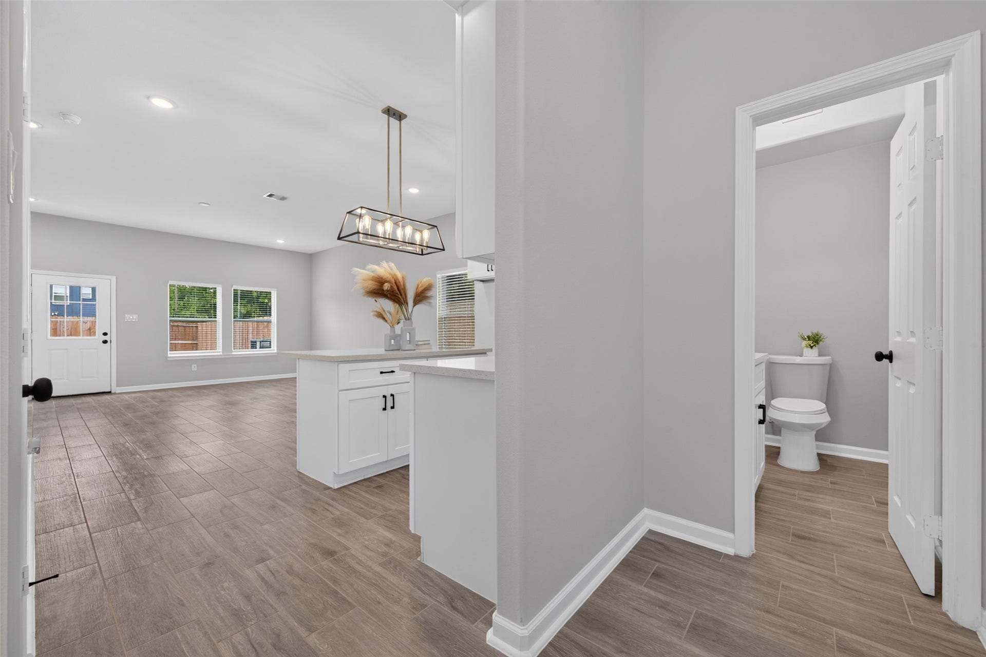 5915 Haight Street, #A, Houston, TX 77028 Bright and open floor plan featuring modern tile flooring, a stylish kitchen island with pendant lighting, and convenient access to a half-bathroom.