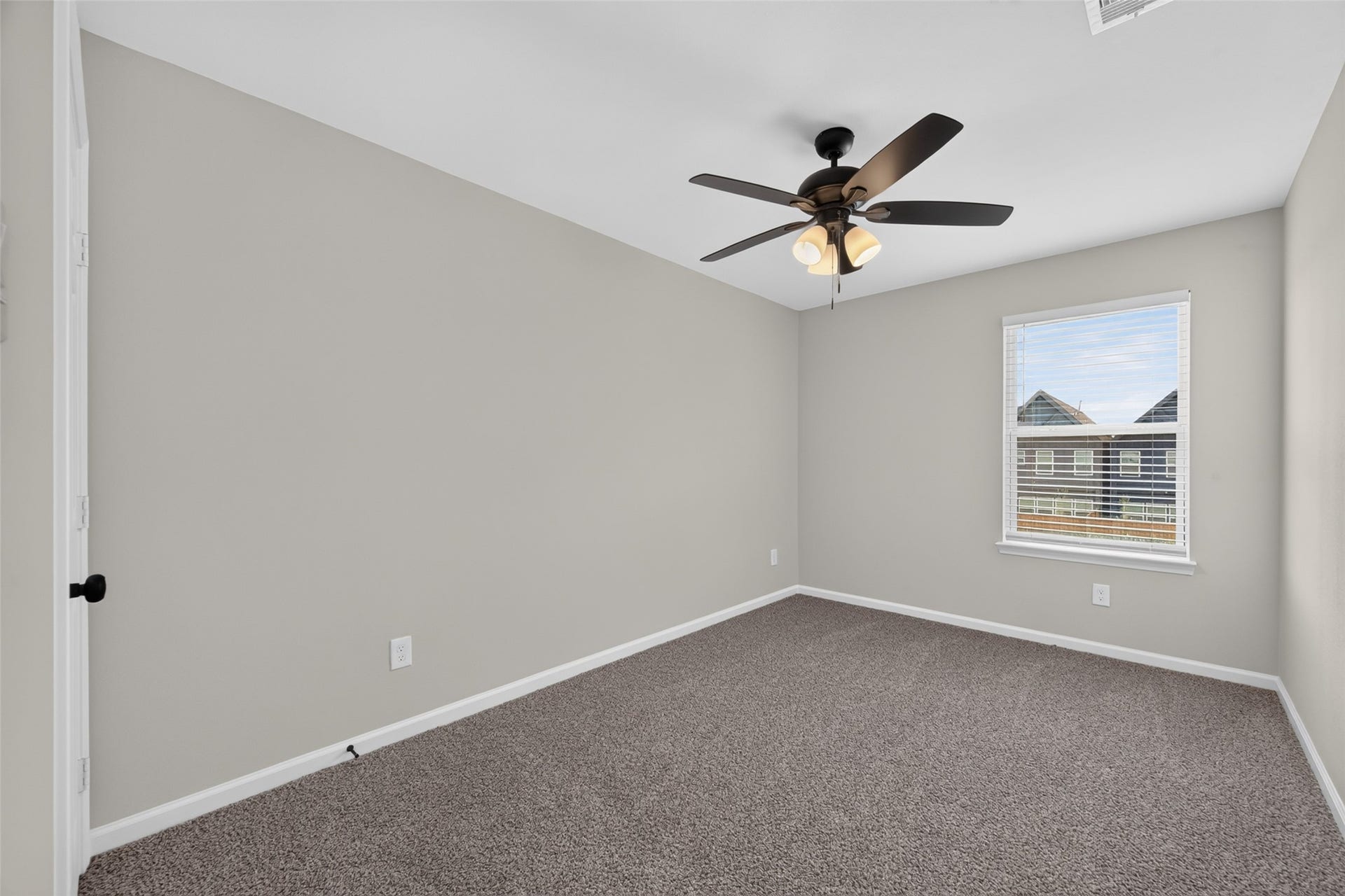 5915 Haight Street, #A, Houston, TX 77028 Bedroom with soft carpeting, neutral walls, and a ceiling fan, offering ample natural light through a large window.