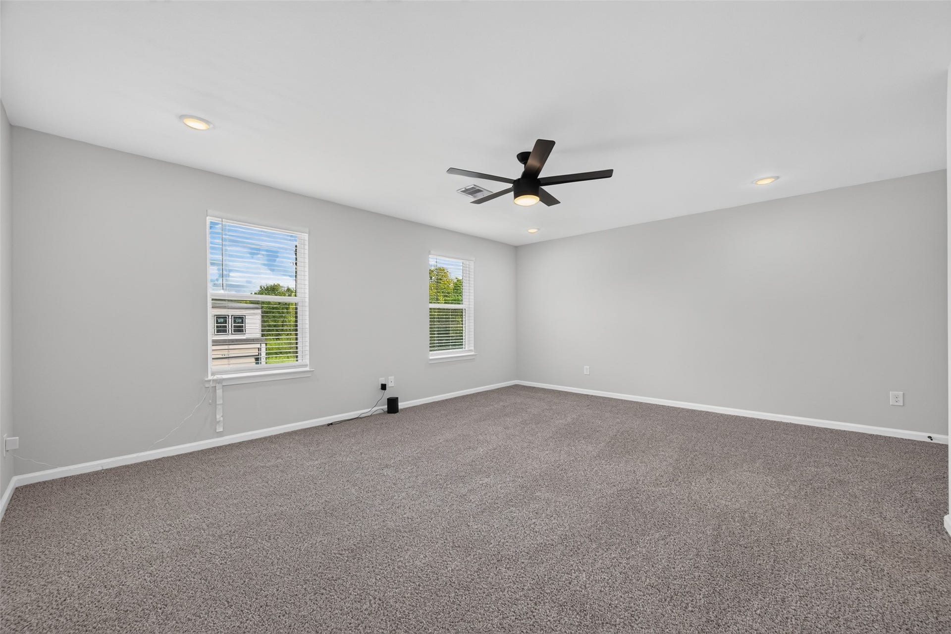 5915 Haight Street, #A, Houston, TX 77028 Spacious, sunlit room with plush carpeting, modern ceiling fan, and neutral walls, perfect for versatile living.