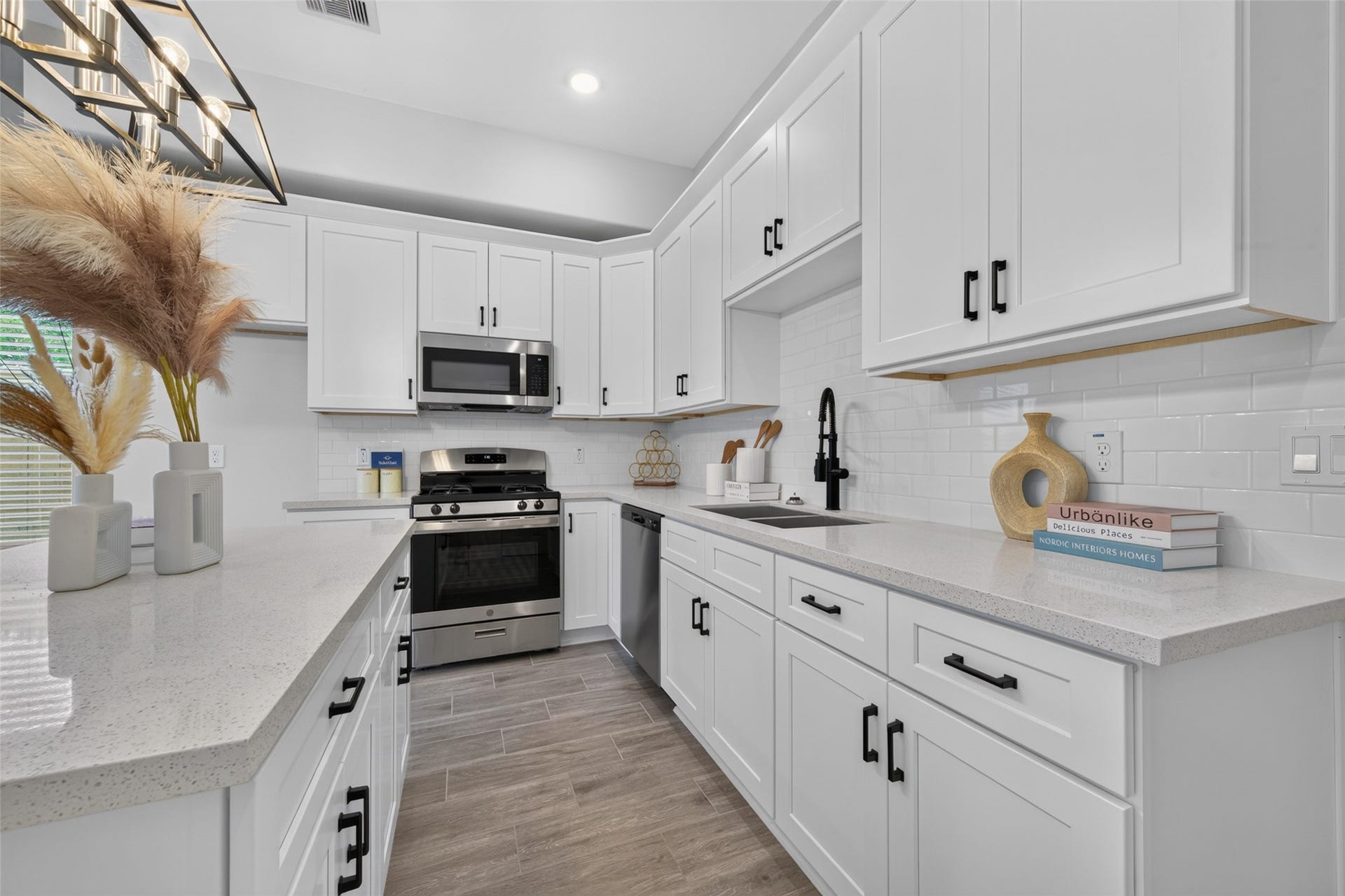 5915 Haight Street, #A, Houston, TX 77028 A bright, modern kitchen with sleek white cabinetry, stainless steel appliances, and elegant black fixtures. The countertops offer ample workspace, complemented by stylish subway tile backsplash and contemporary lighting.