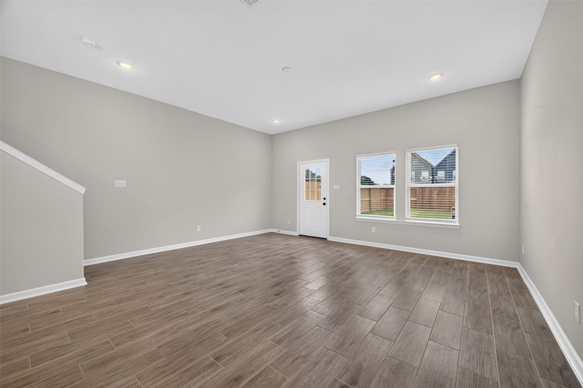5915 Haight Street, #A, Houston, TX 77028 Spacious living area with elegant wood-look tile flooring, neutral walls, and abundant natural light from large windows and a glass door leading to the backyard.