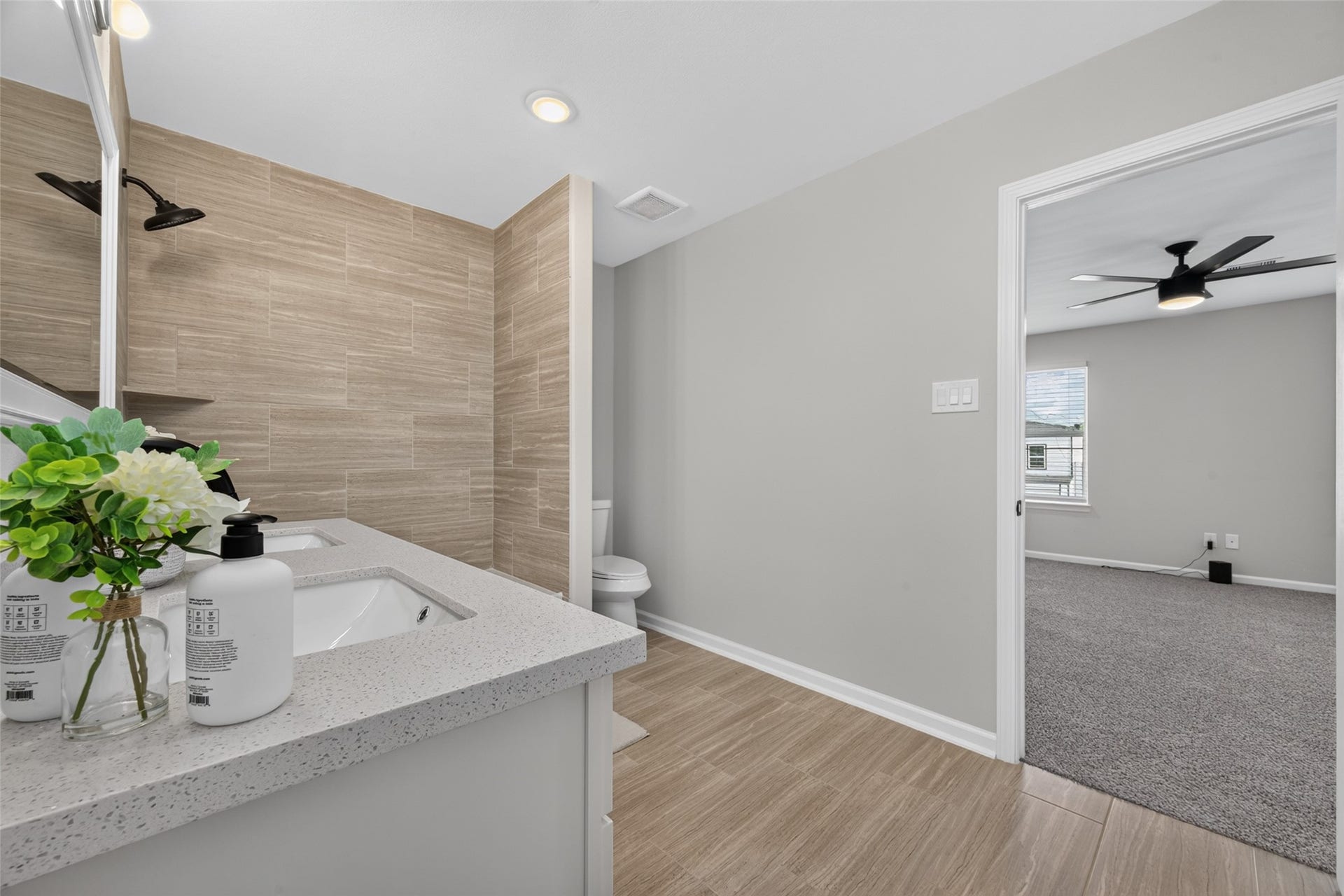 5915 Haight Street, #A, Houston, TX 77028 Stylish bathroom with modern fixtures, featuring a sleek vanity and elegant tile work, seamlessly connected to a cozy bedroom with plush carpeting and a ceiling fan.