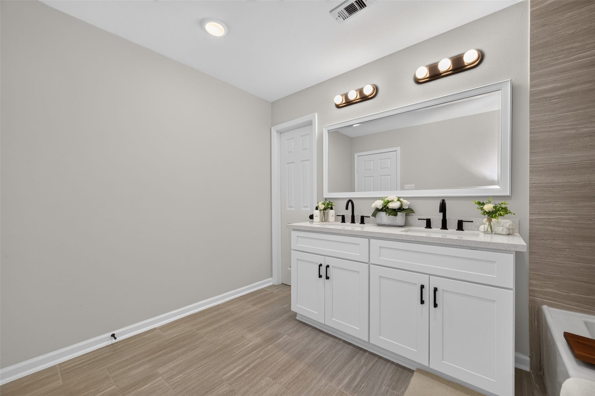 5915 Haight Street, #A, Houston, TX 77028 Elegant bathroom featuring a double vanity with sleek black fixtures, large mirror, and ample counter space, complemented by soft lighting and neutral tones.