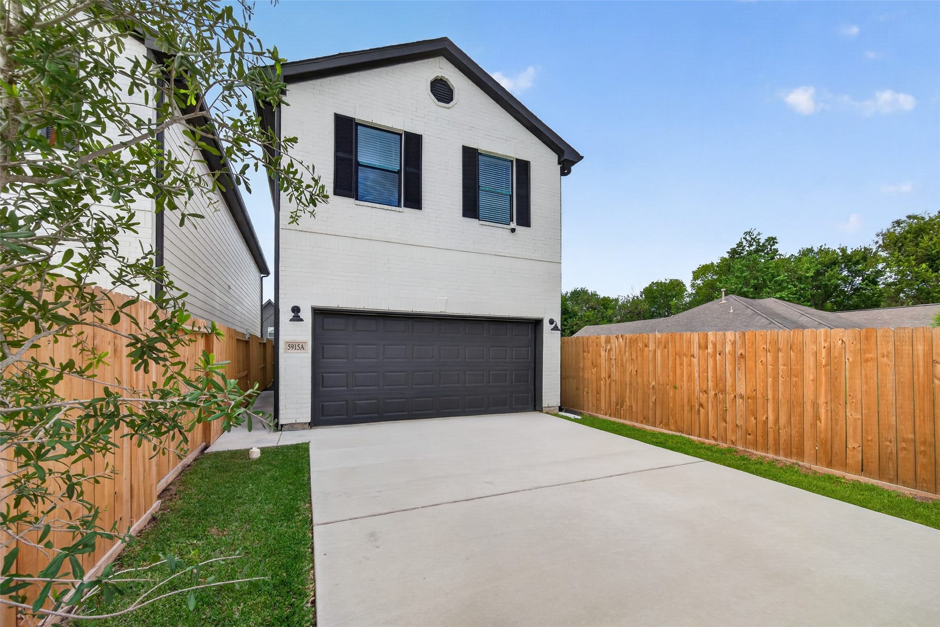 5915 Haight Street, #A, Houston, TX 77028 exterior, dark shutters, and a spacious double garage, framed by a secure wooden fence and a well-maintained driveway.