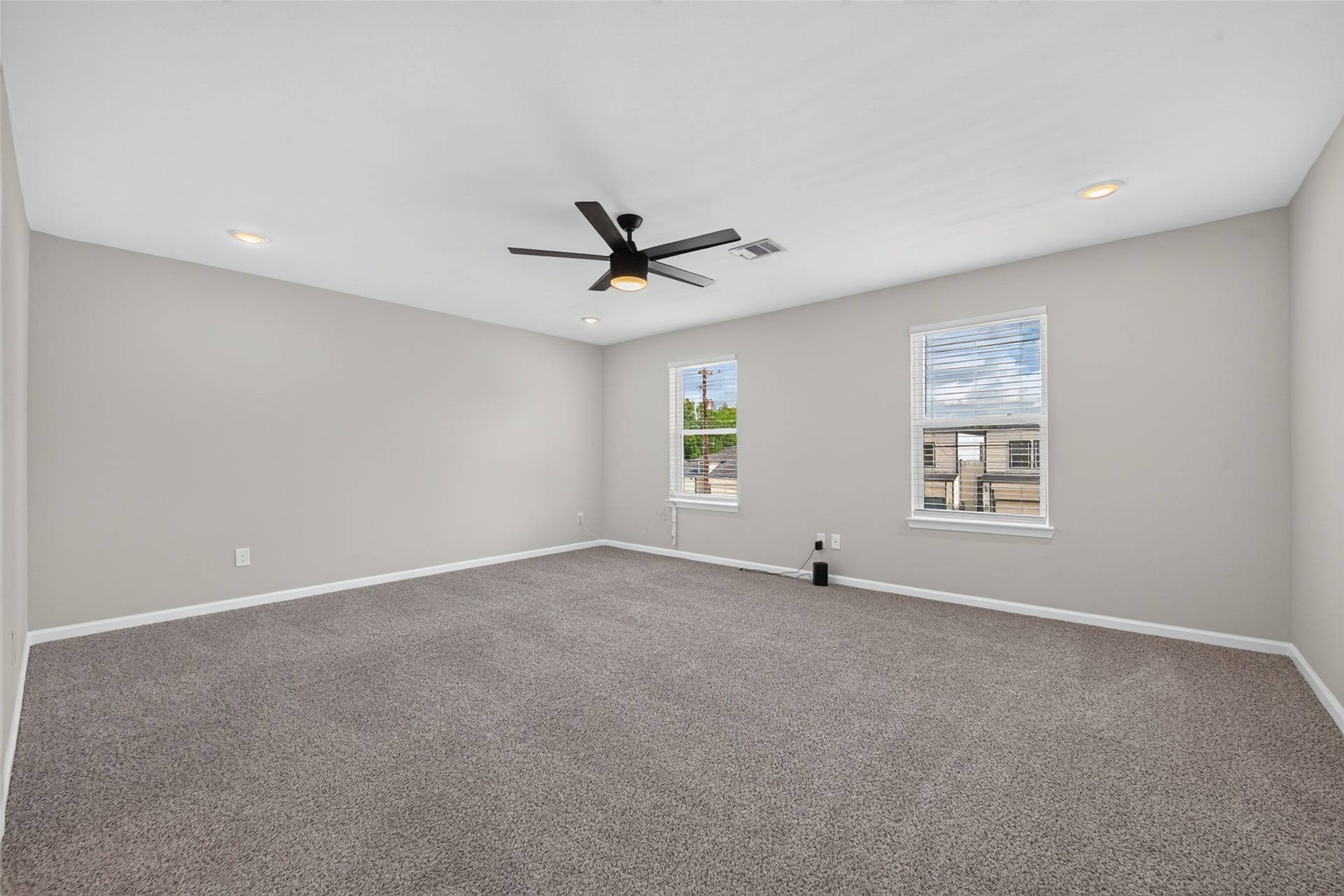 5915 Haight Street, #A, Houston, TX 77028 Spacious, light-filled room with neutral tones, plush carpeting, and a modern ceiling fan, perfect for versatile living arrangements.