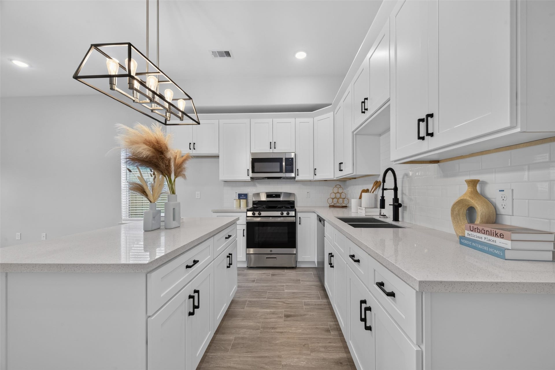 5915 Haight Street, #A, Houston, TX 77028 Modern kitchen with sleek white cabinetry, stainless steel appliances, and a spacious island featuring stylish lighting.