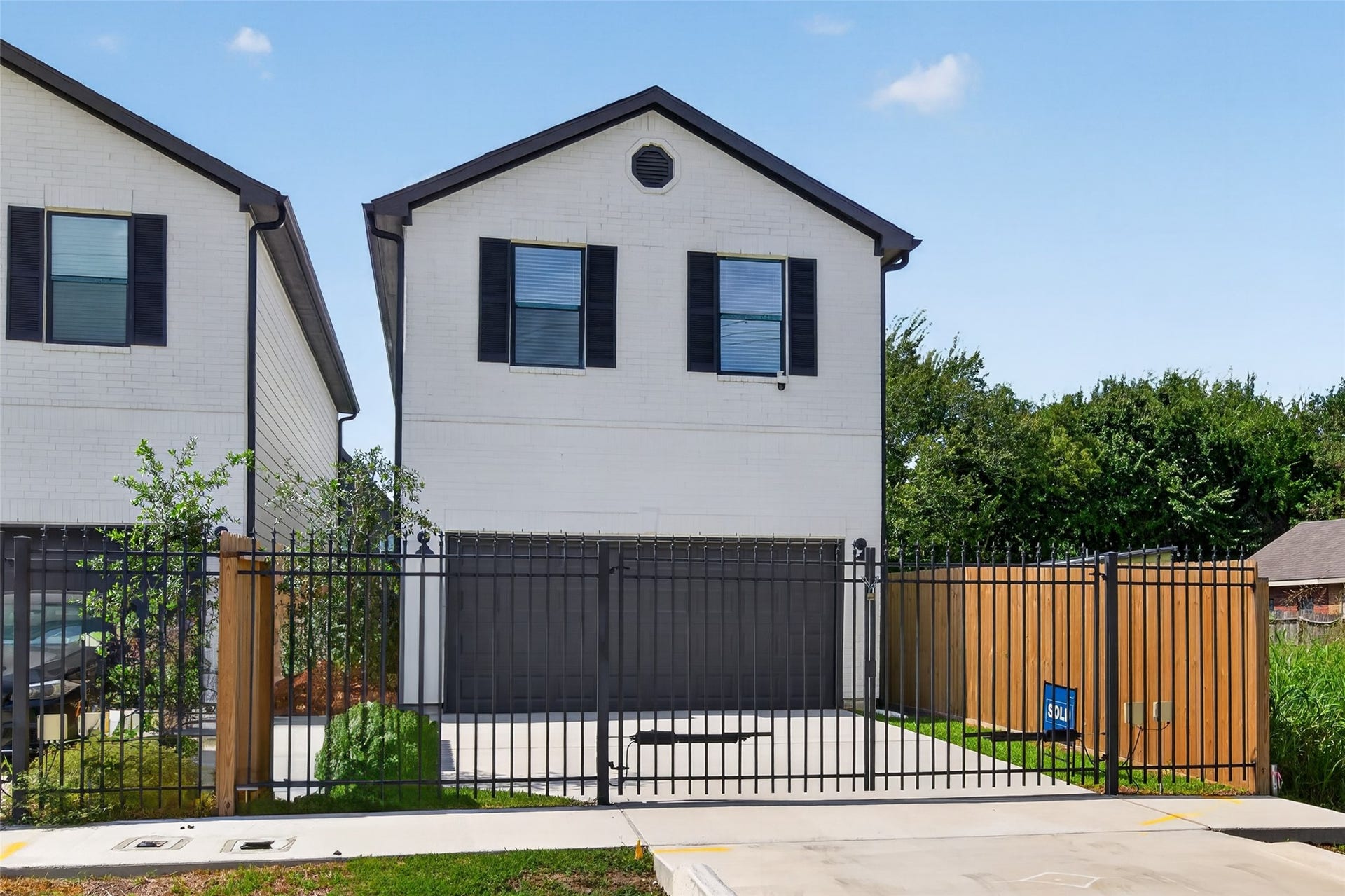 5915 Haight Street, #A, Houston, TX 77028 Modern two-story home with a sleek black fence, spacious driveway, and charming shutters, offering privacy and contemporary style.