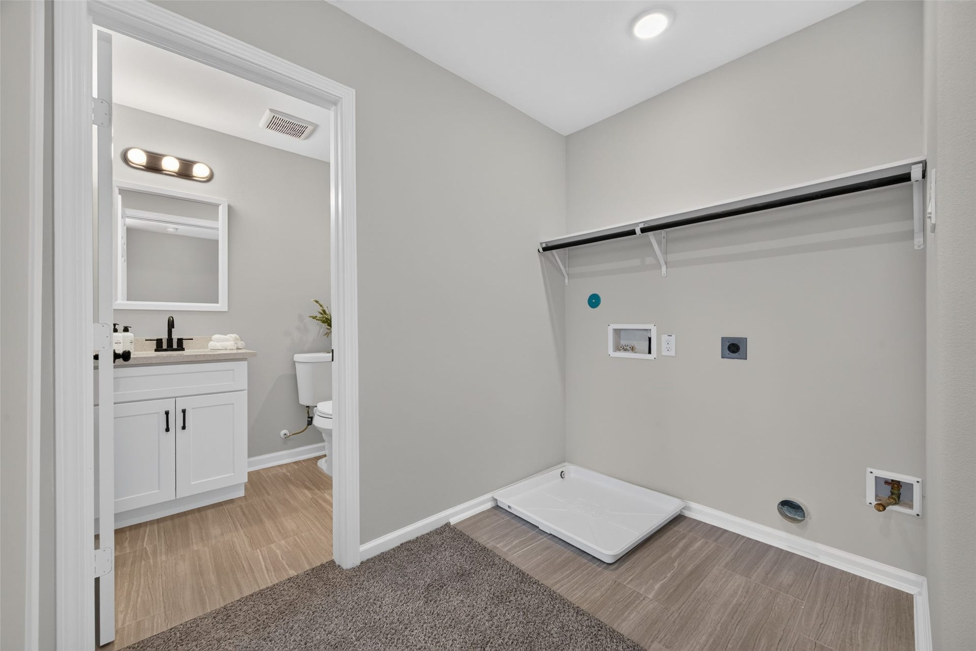 5915 Haight Street, #A, Houston, TX 77028 Spacious laundry room with utility connections, adjacent to a modern bathroom featuring a sleek vanity and bright lighting.