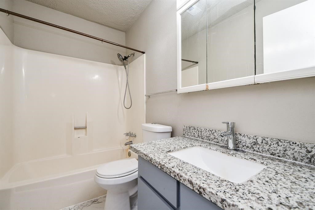 12569 Wellington Park Drive, Houston, TX 77072 This bathroom features a clean, modern design with a granite countertop, an undermount sink, and a tub-shower combo. The neutral color palette and ample mirror space create a bright, functional space.