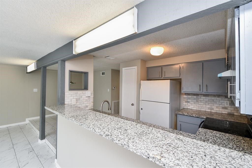 12569 Wellington Park Drive, Houston, TX 77072 Modern kitchen with granite countertops, ample cabinet space, and a breakfast bar. Neutral tones and tile flooring create a bright, open atmosphere.