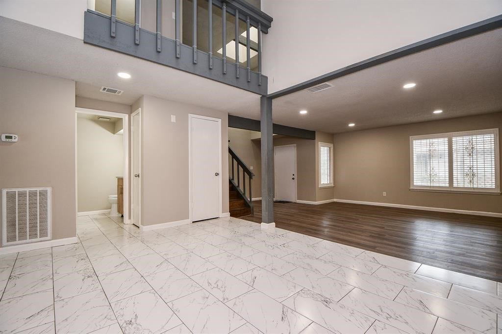 12569 Wellington Park Drive, Houston, TX 77072 This spacious living area features a modern open layout with high ceilings, a mix of marble and wood flooring, and ample natural light from large windows. An upstairs loft overlooks the main space, adding a touch of elegance.