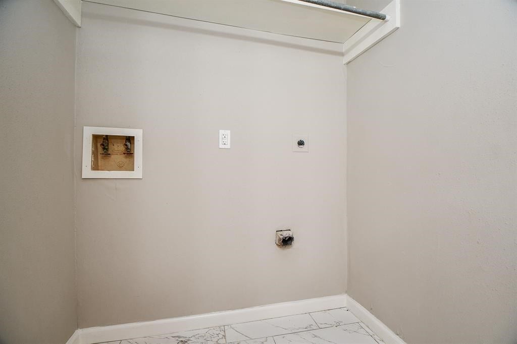 12569 Wellington Park Drive, Houston, TX 77072 This photo shows a laundry area with hookups for a washer and dryer. It features light-colored walls and tiled flooring, providing a clean and functional space for laundry appliances.