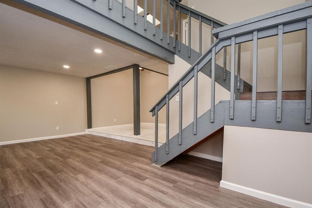 12569 Wellington Park Drive, Houston, TX 77072 This photo showcases a modern interior with laminate wood flooring, a two-tone staircase with gray railings, and recessed lighting, offering a spacious and open feel.