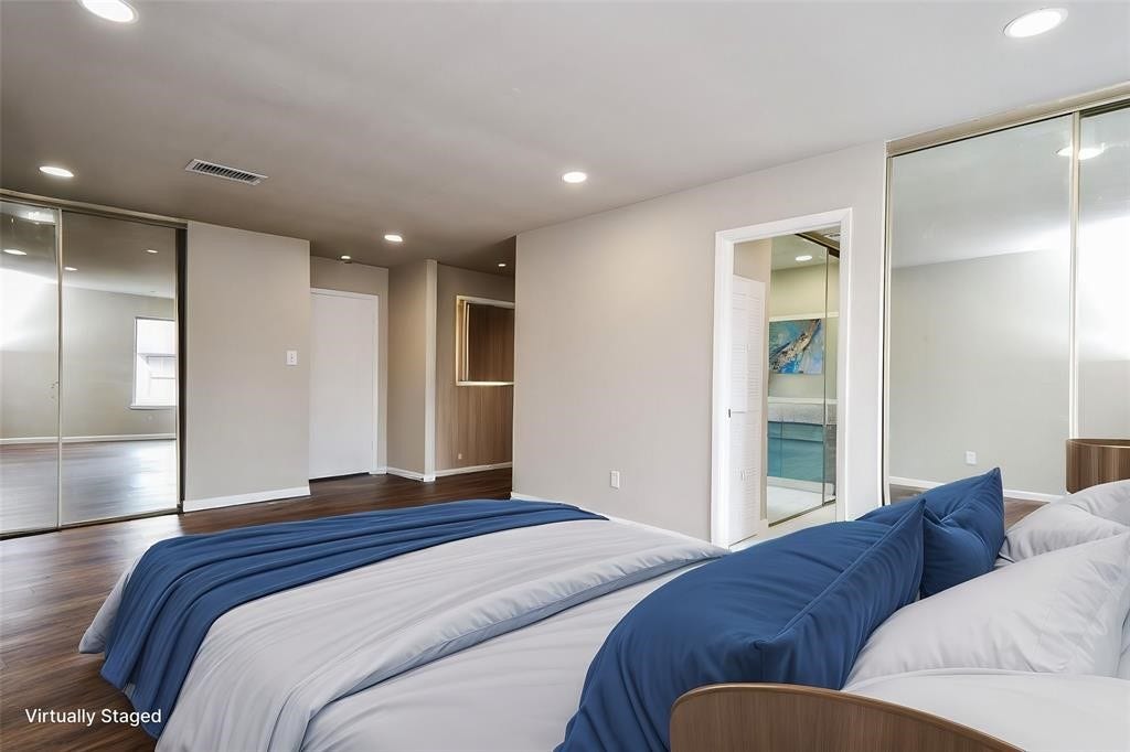 12569 Wellington Park Drive, Houston, TX 77072 This virtually staged bedroom features a spacious layout with hardwood floors, recessed lighting, and mirrored closet doors. The neutral walls provide a fresh feel, and an ensuite bathroom offers added convenience. Virtual staging was used.