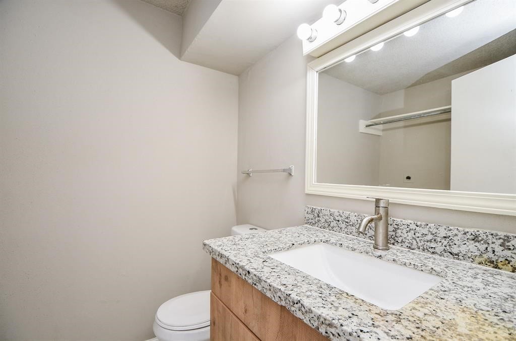 12569 Wellington Park Drive, Houston, TX 77072 This bathroom features a modern granite countertop with an under-mount sink, a sleek faucet, and a large framed mirror with overhead lighting. The neutral walls create a clean and spacious feel.
