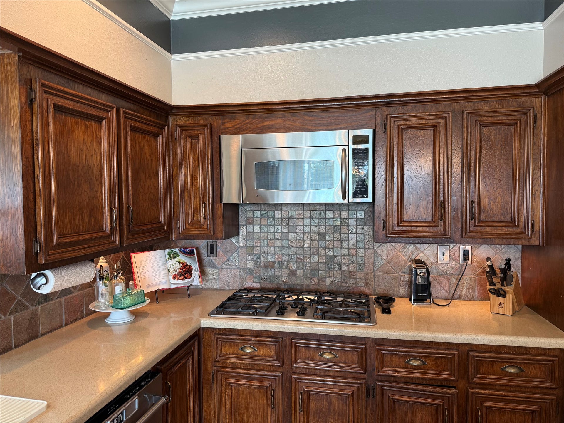 Experience culinary convenience with a sleek built-in microwave and gas range, set against a backdrop of rich cabinetry and a bright, inviting kitchen space.