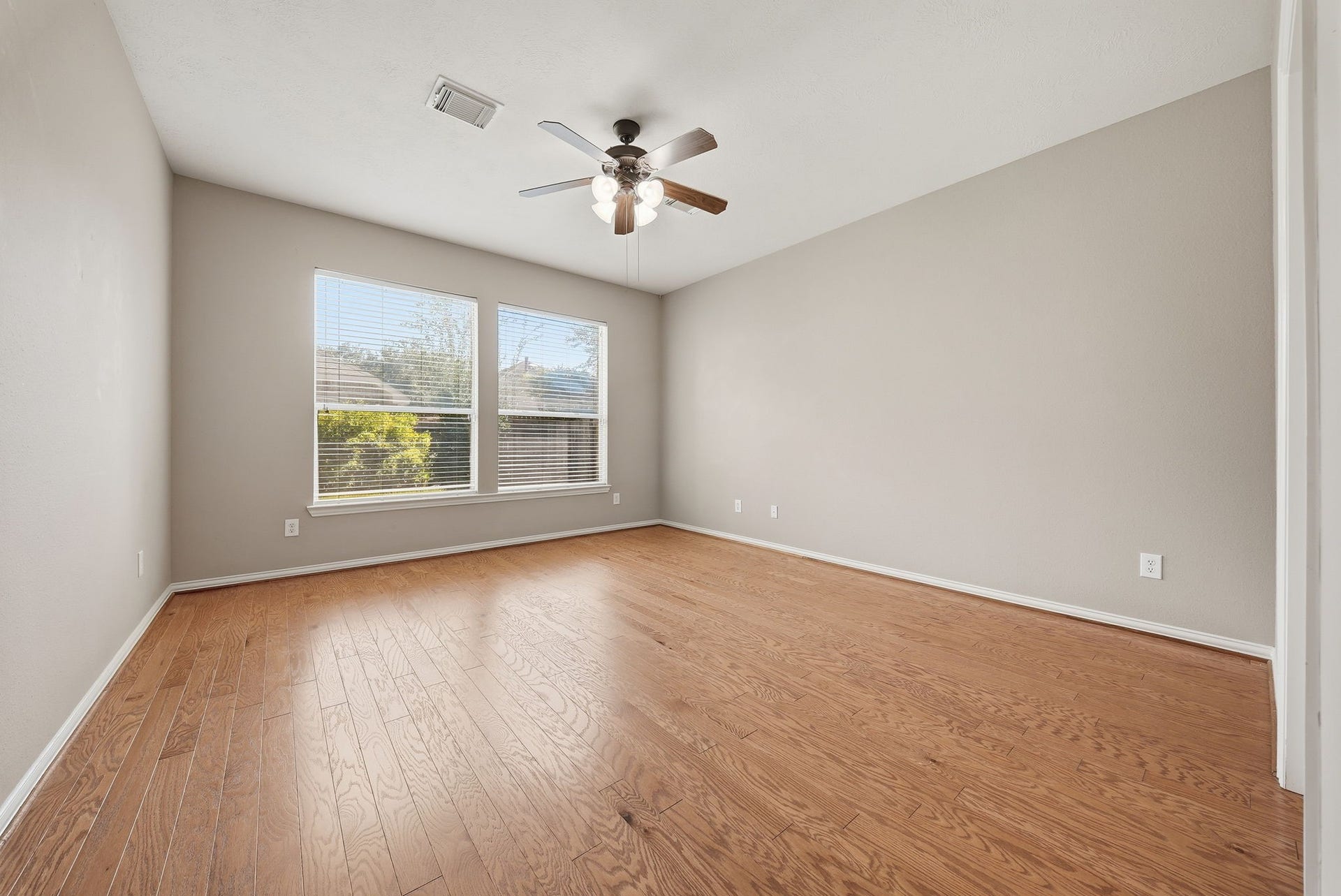 Downstairs primary bedroom offers high ceilings, abundant natural light, and carpet-free flooring for a comfortable retreat.
