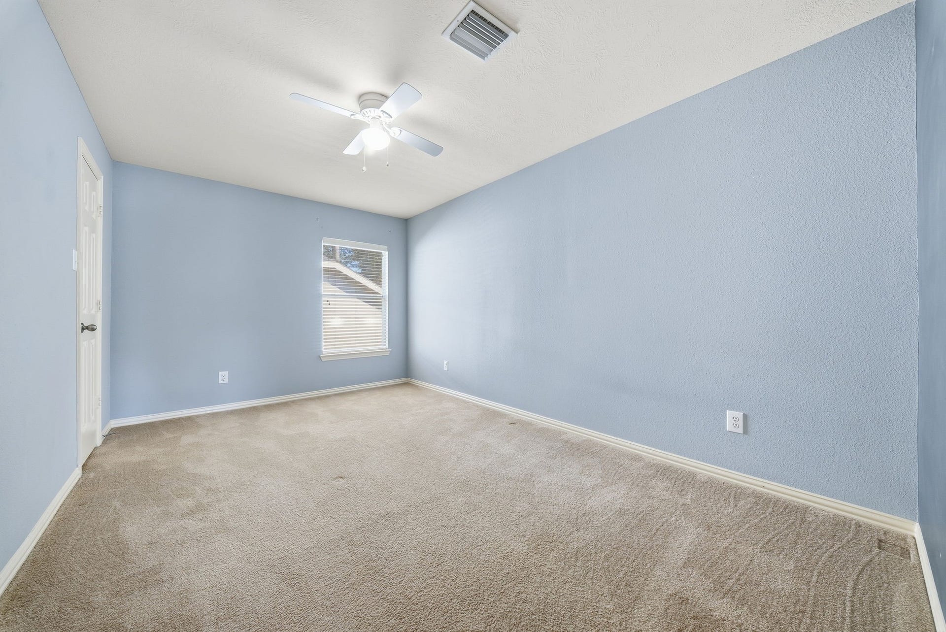 Bedroom 3 located upstairs, offers ample room for a bed, dresser, and study space, with natural light and a ceiling fan for added comfort.