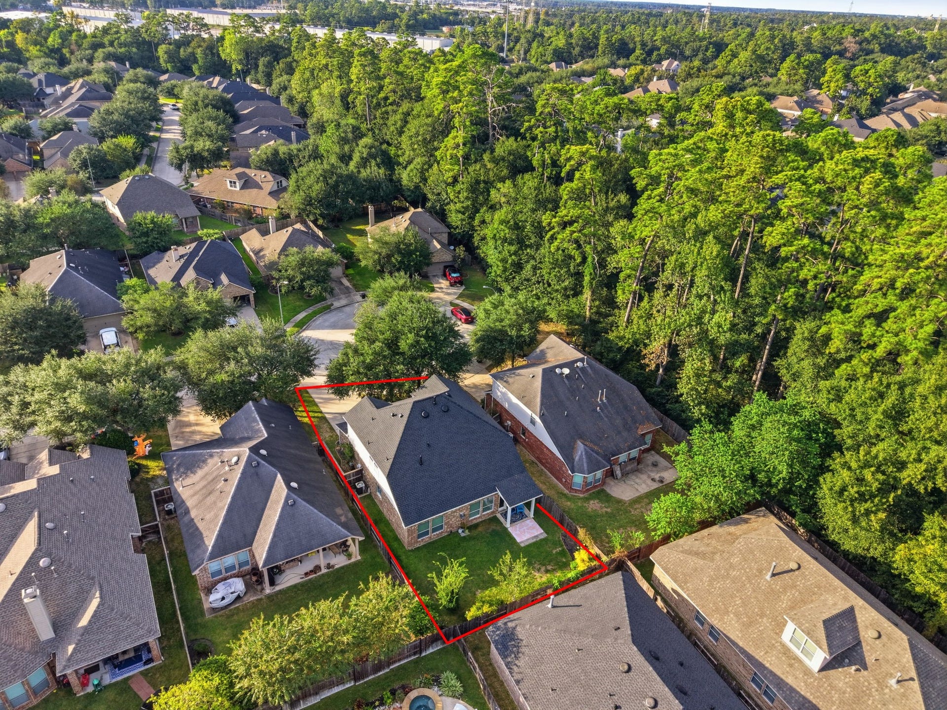 A wider aerial perspective showcases the surrounding tree canopy and the homes position within an established neighborhood.