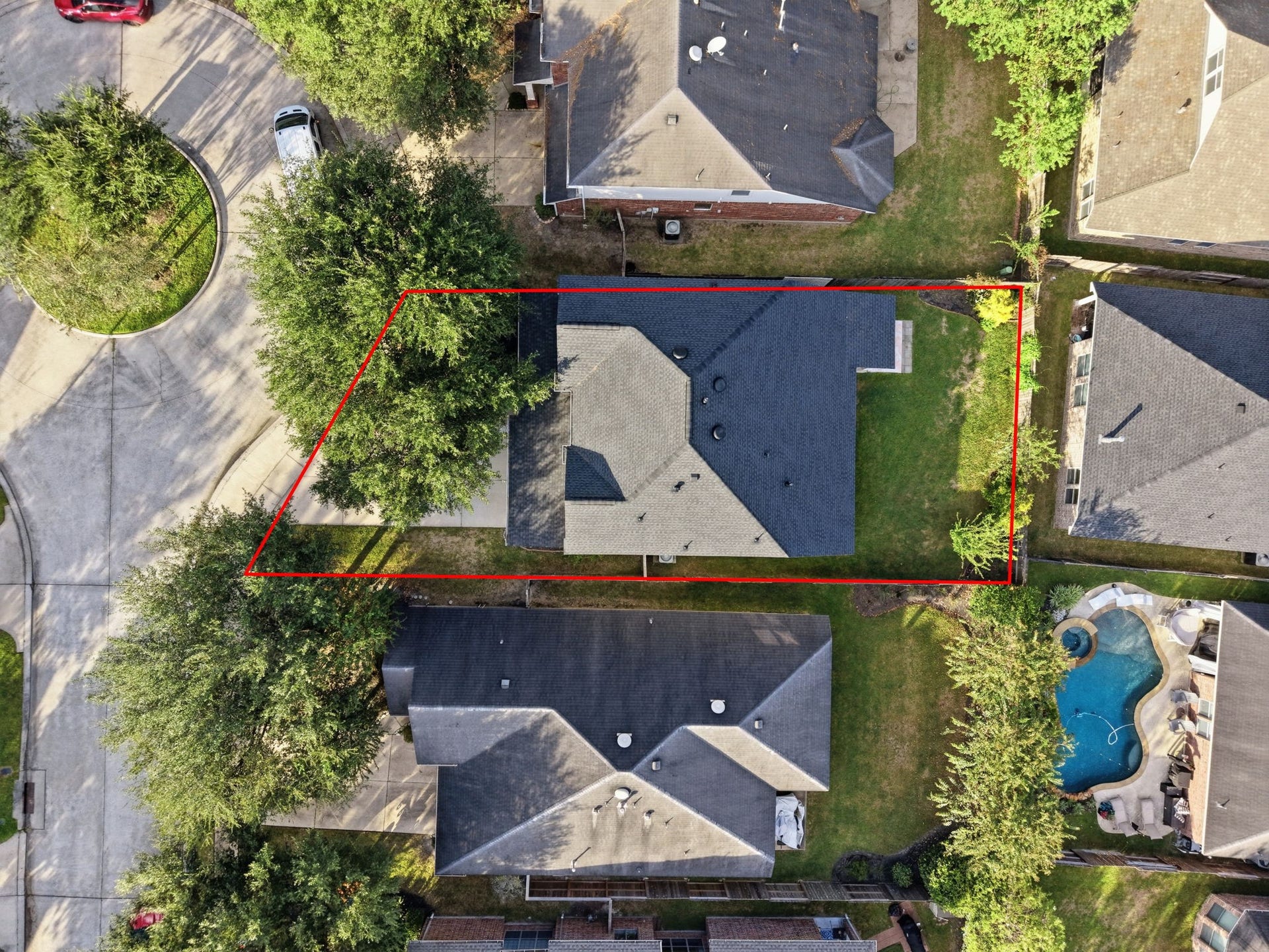 Aerial view highlights the homes cul-de-sac setting, mature shade trees, and fenced backyard, with the approximate lot outline shown in red.