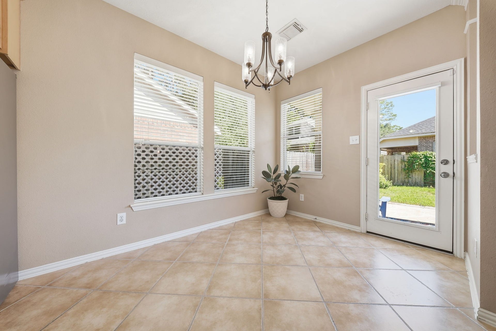 Windows throughout the breakfast area fill the space with natural light, while a backyard door with a large glass pane offers outdoor views and easy access for patio dining.