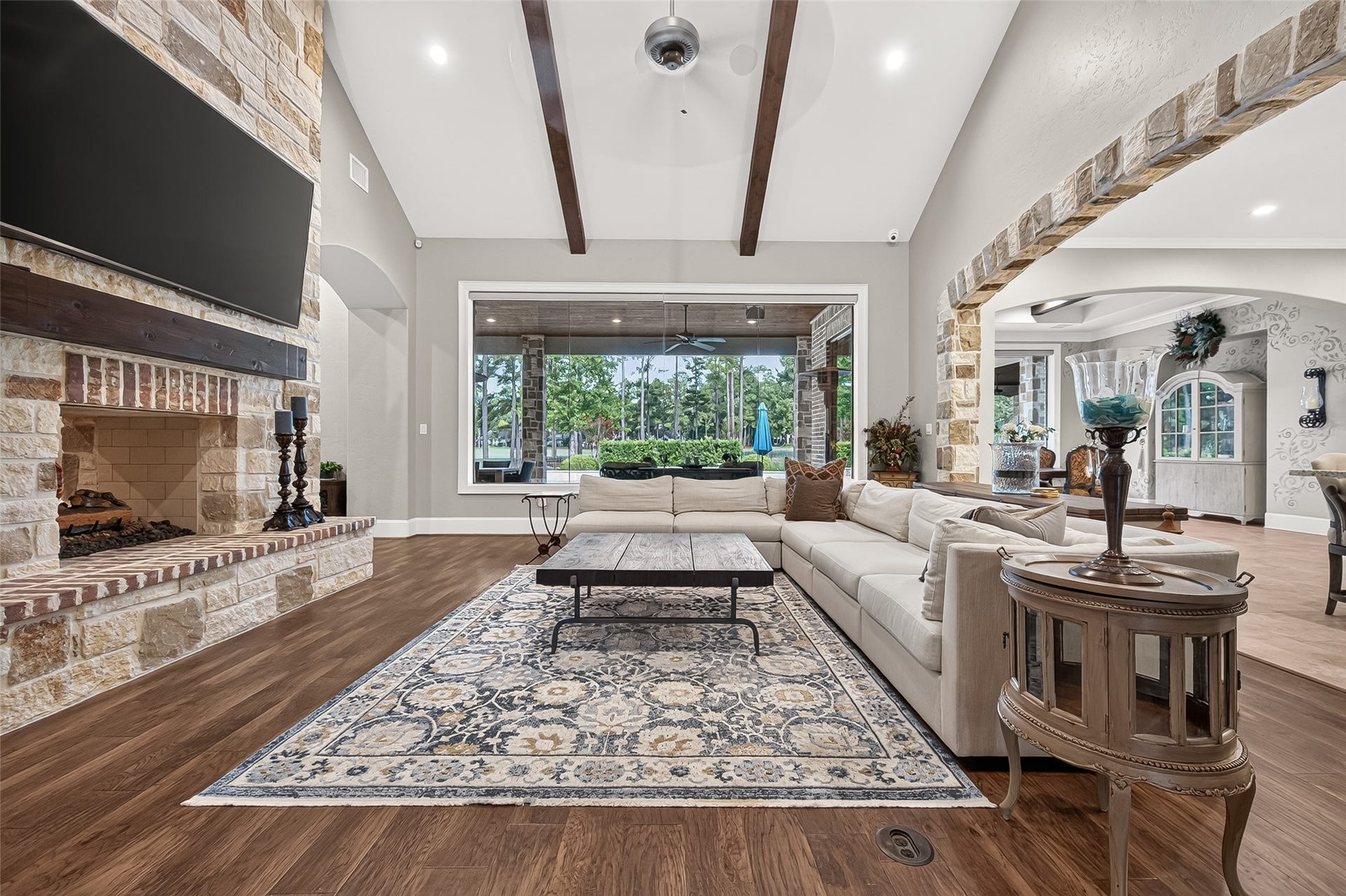 28723 Post Oak Run, Magnolia, TX 77355 Family room with a vaulted, beamed ceiling and a floor-to-ceiling stone fireplace, plus oversized picture window looking out to the covered patio and pool area.