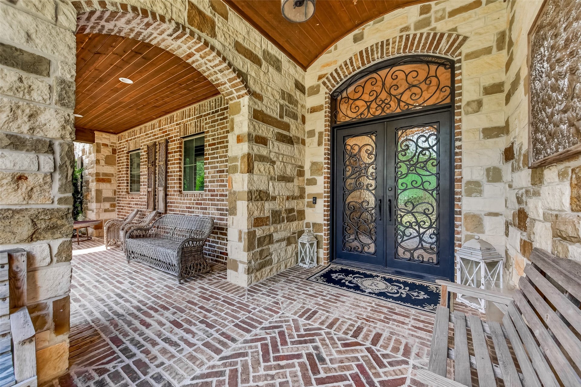 28723 Post Oak Run, Magnolia, TX 77355 Covered front porch with stone arches, a stained tongue-and-groove ceiling and a herringbone brick floor. Arched wrought-iron double doors open to the foyer.