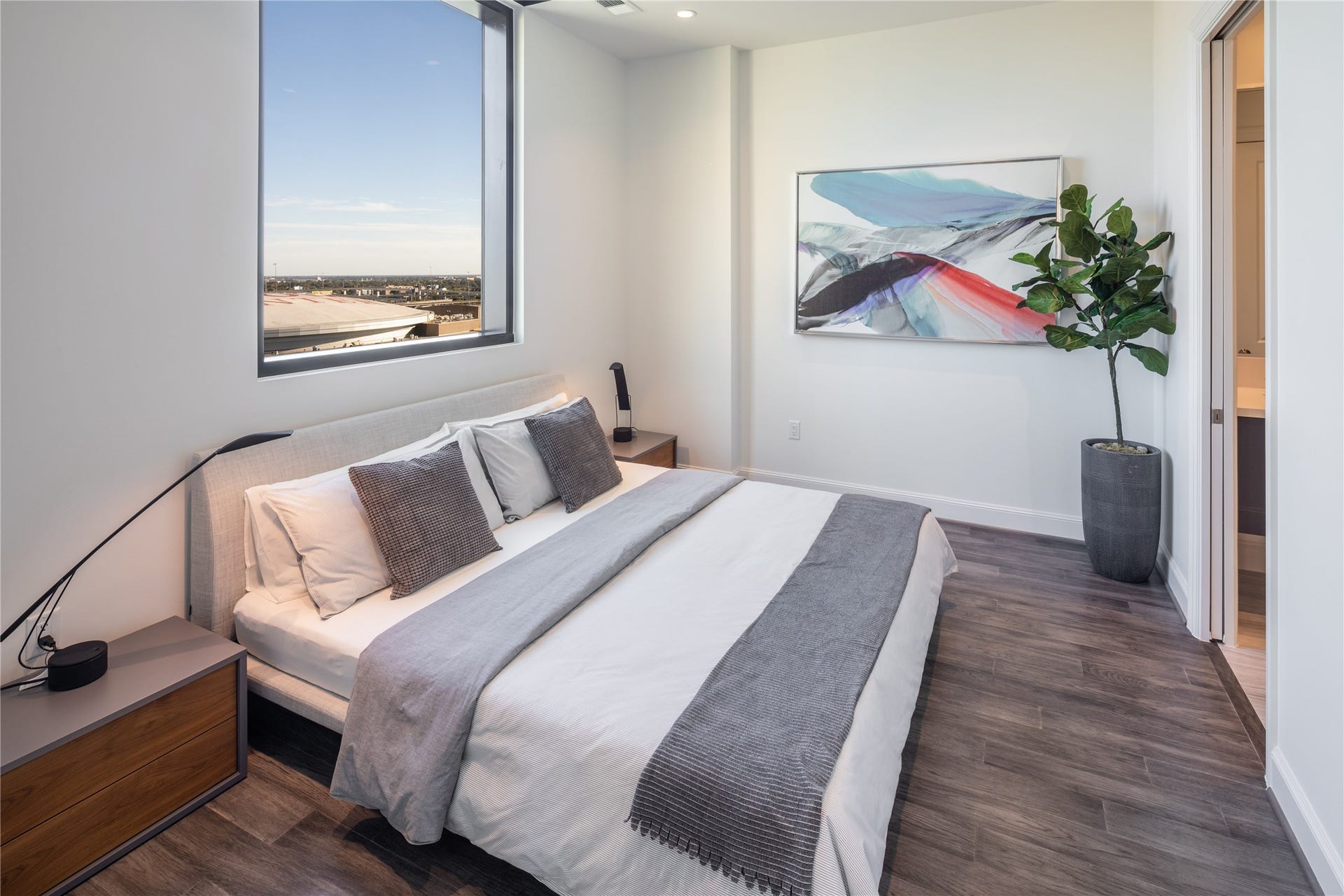 [Primary Bedroom VIRTUALLY STAGED]  Primary bedroom boasting elegant hardwoods and picture window, suitable for king size bed