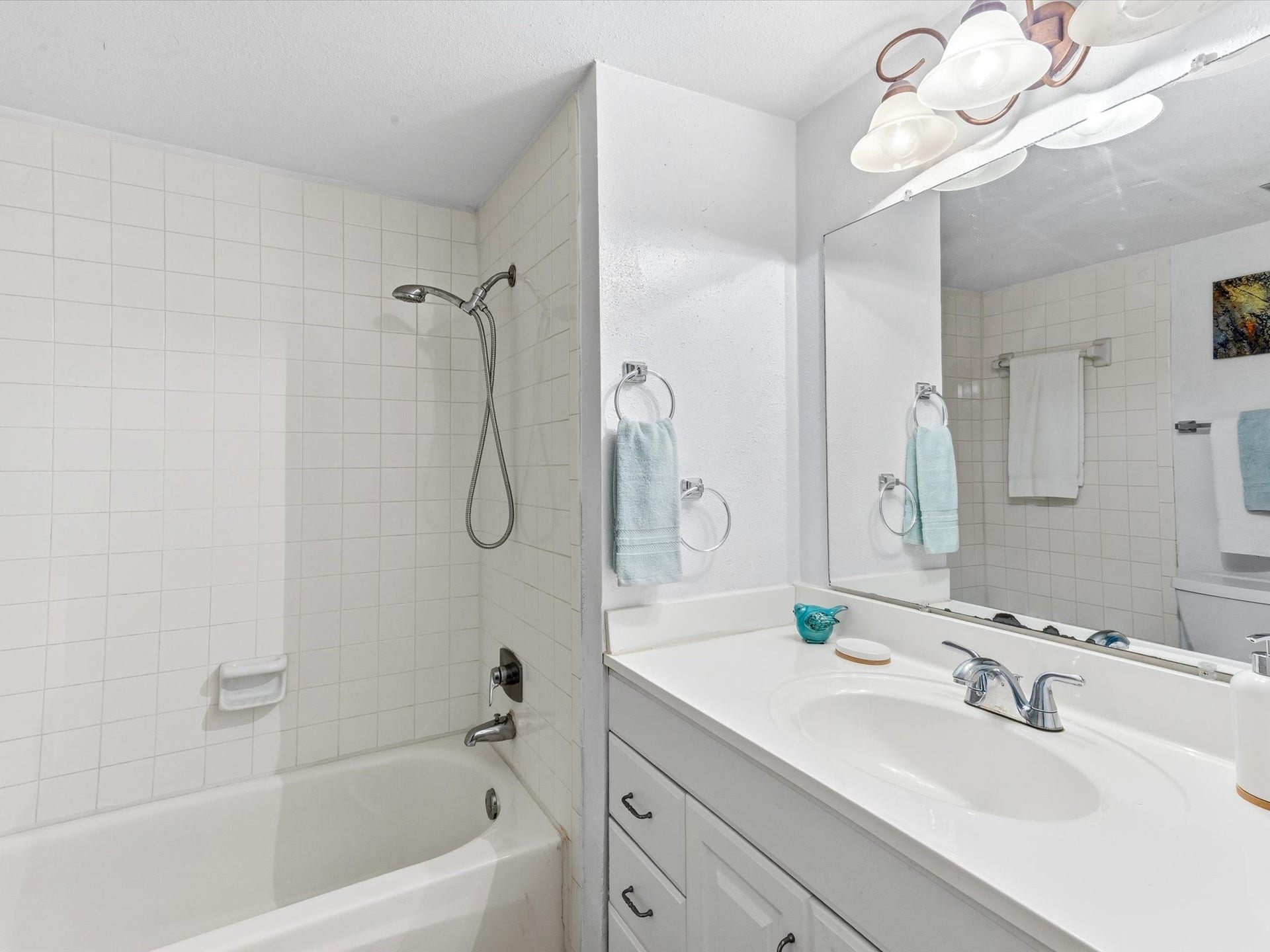 Bright bathroom featuring a spacious vanity, large mirror, and shower and tub combination.