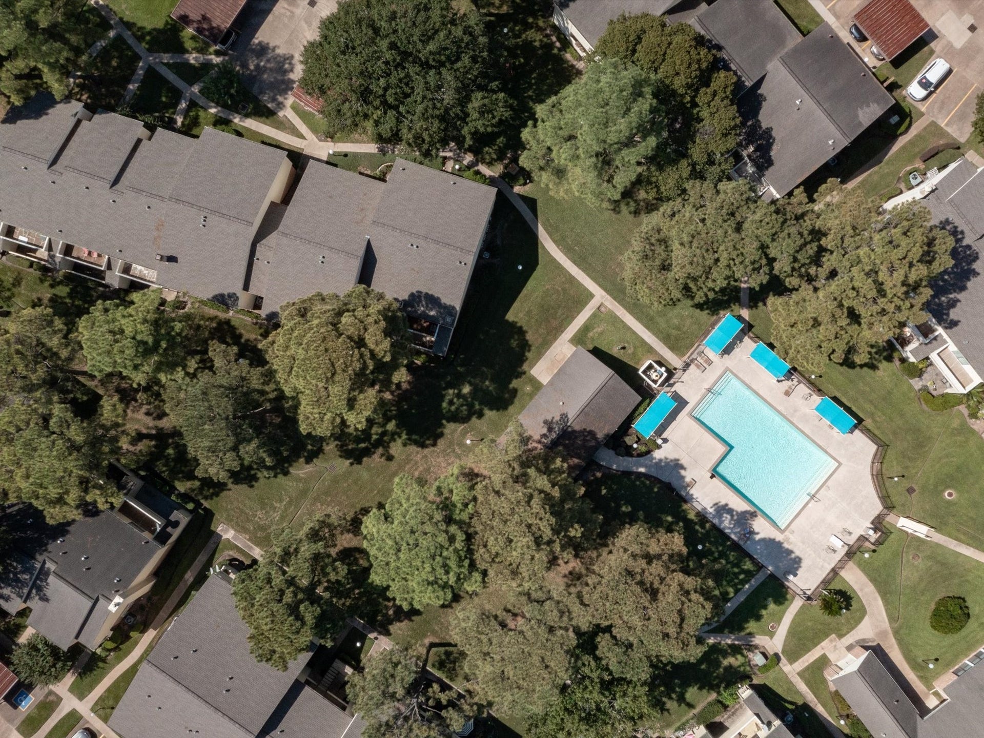 Aerial view highlighting the community pool, surrounding buildings, and beautifully landscaped grounds.