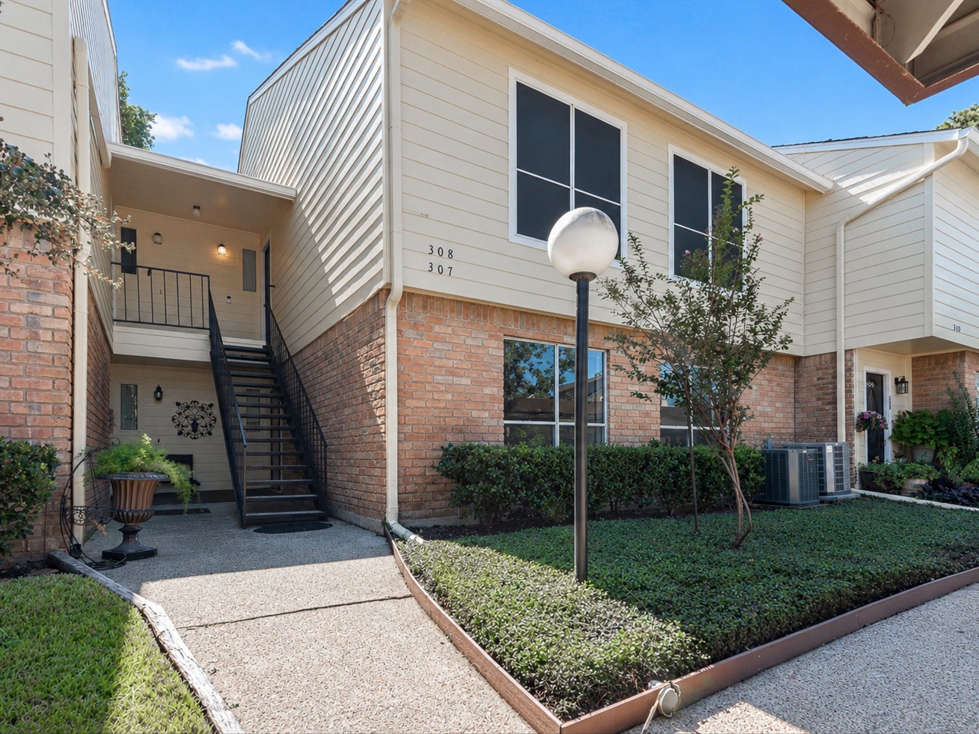 Condo's exterior, featuring landscaped surroundings and a walkway leading to the entrance.