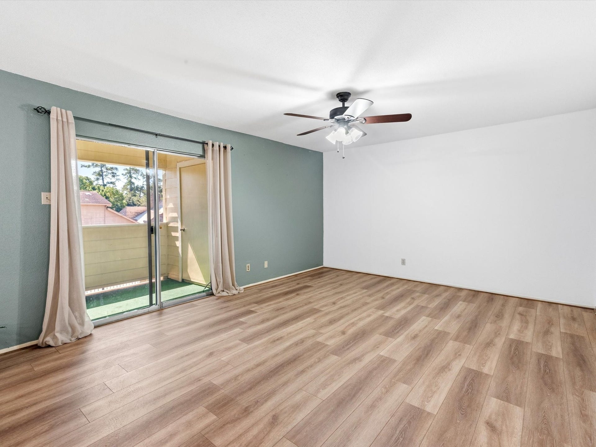 Living room with a ceiling fan and large sliding glass doors overlooking the patio.