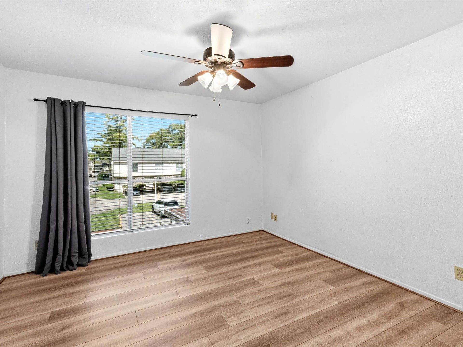 Another view of the bedroom, featuring a ceiling fan and large window that fills the room with natural light.
