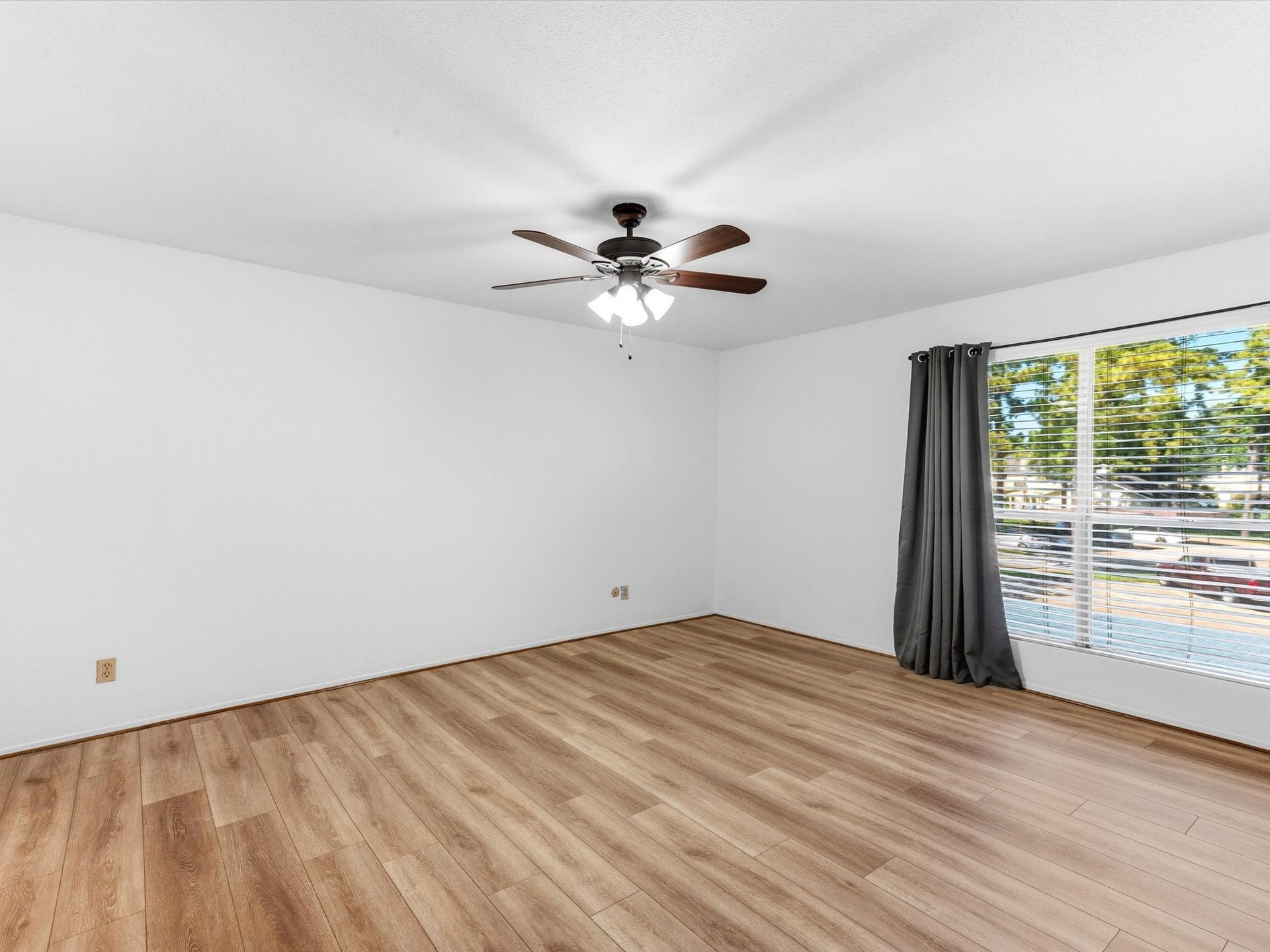 Bright bedroom with a ceiling fan and large window overlooking the outdoors.