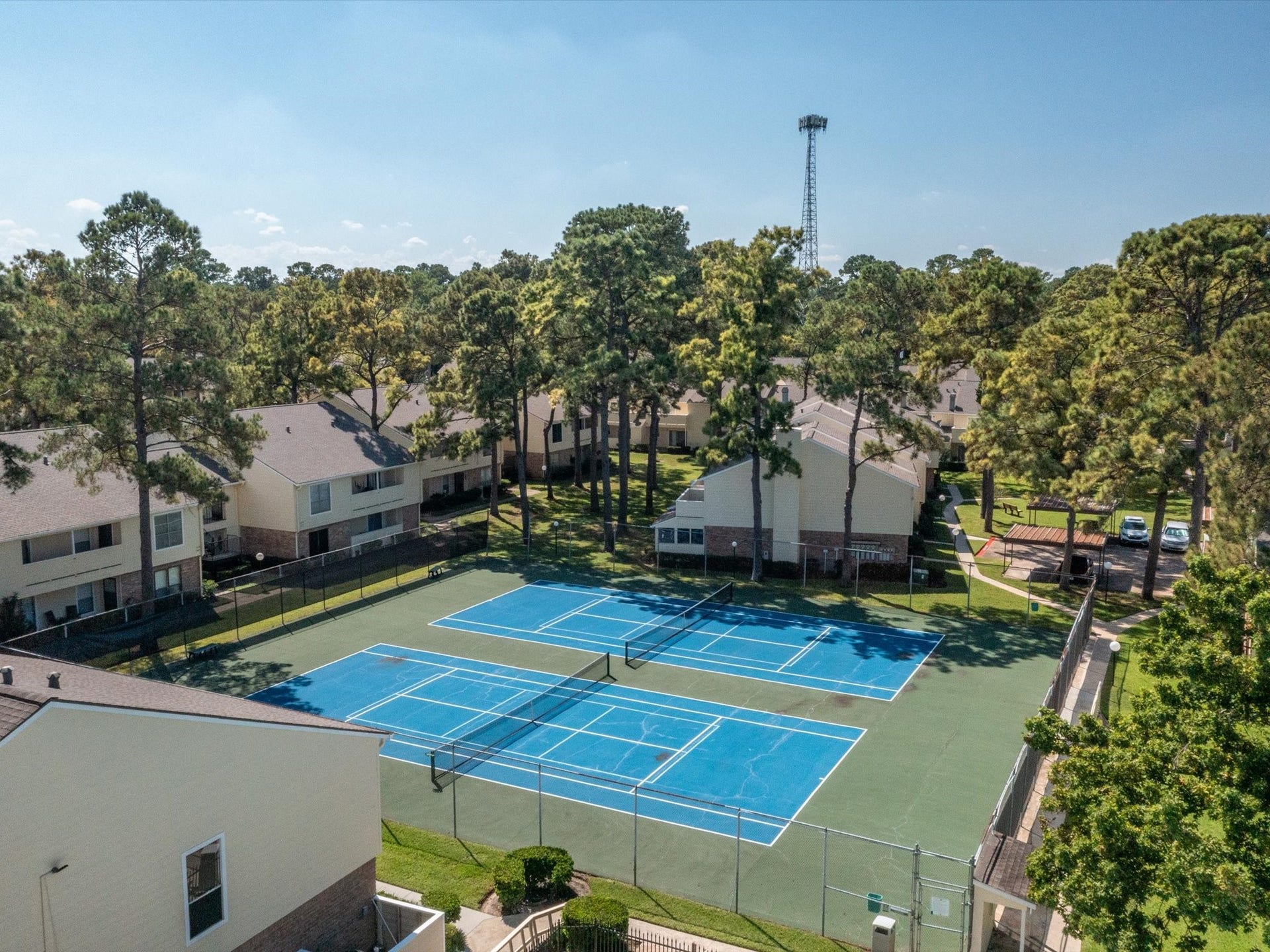 Elevated view of the tennis courts nestled among the community's mature trees.