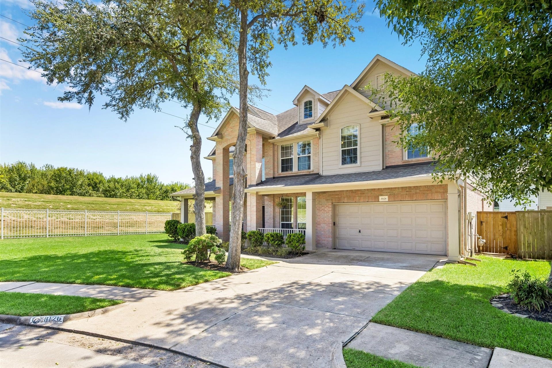 8126 BUFFALO SPRINGS COURT, Sugar Land, TX 77479 BEAUTIFUL FRONT ELEVATION SHOWCASING A SPACIOUS LAWN, MATURE TREES, AND AN OPEN GREENSPACE SETTING ALONG THE SIDE OF THE PROPERTY.