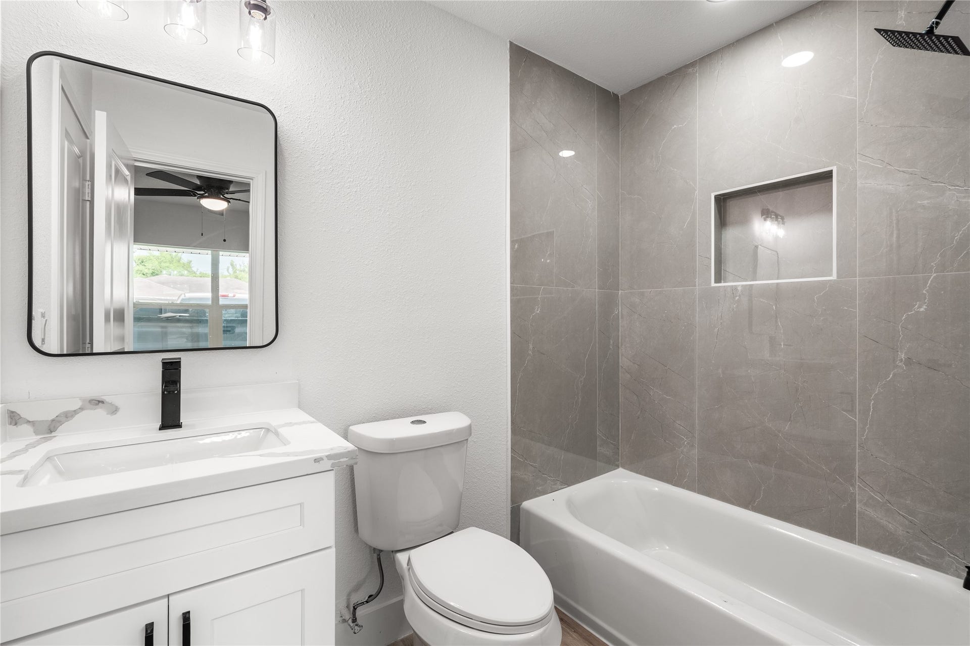 3048 Briarwick Lane, Houston, TX 77093 Elegant full bath boasting stylish matte black hardware, custom gray tile surround, and a pristine white vanityoffering a sophisticated, spa-like feel for guests and family alike.