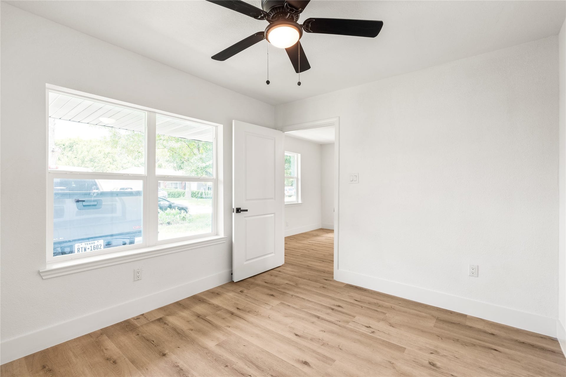 3048 Briarwick Lane, Houston, TX 77093 Light-filled primary bedroom featuring a double window, modern ceiling fan, warm wood-look flooring, and a crisp, seamless entry.