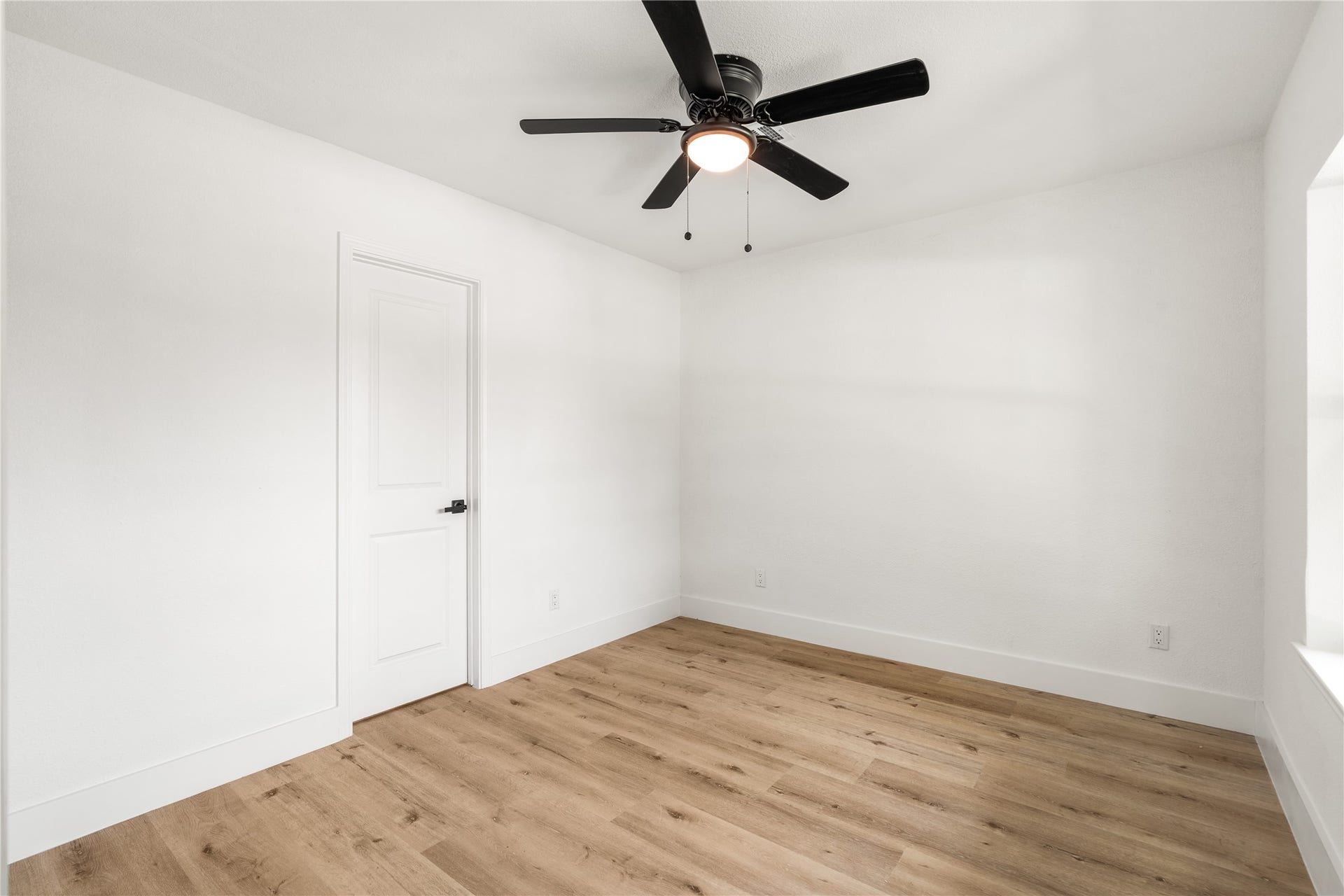 3048 Briarwick Lane, Houston, TX 77093 Reverse view of Bedroom showcasing warm wood-look flooring, crisp neutral walls, and a modern ceiling fan.