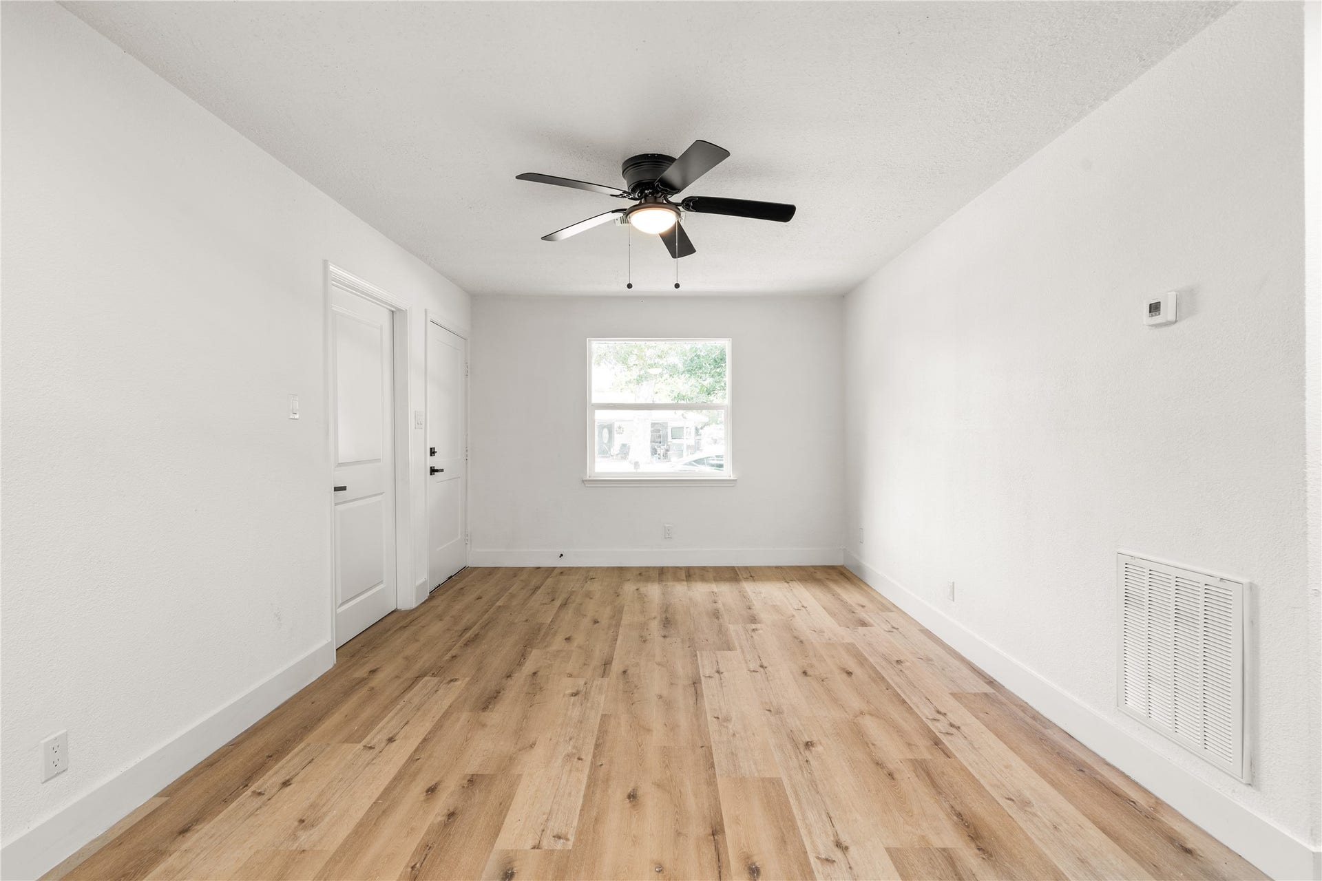 3048 Briarwick Lane, Houston, TX 77093 Living Area: Centered perspective highlighting rich wood-grain floors, fresh neutral finishes, efficient central HVAC features, and a bright focal window framing front-yard views.