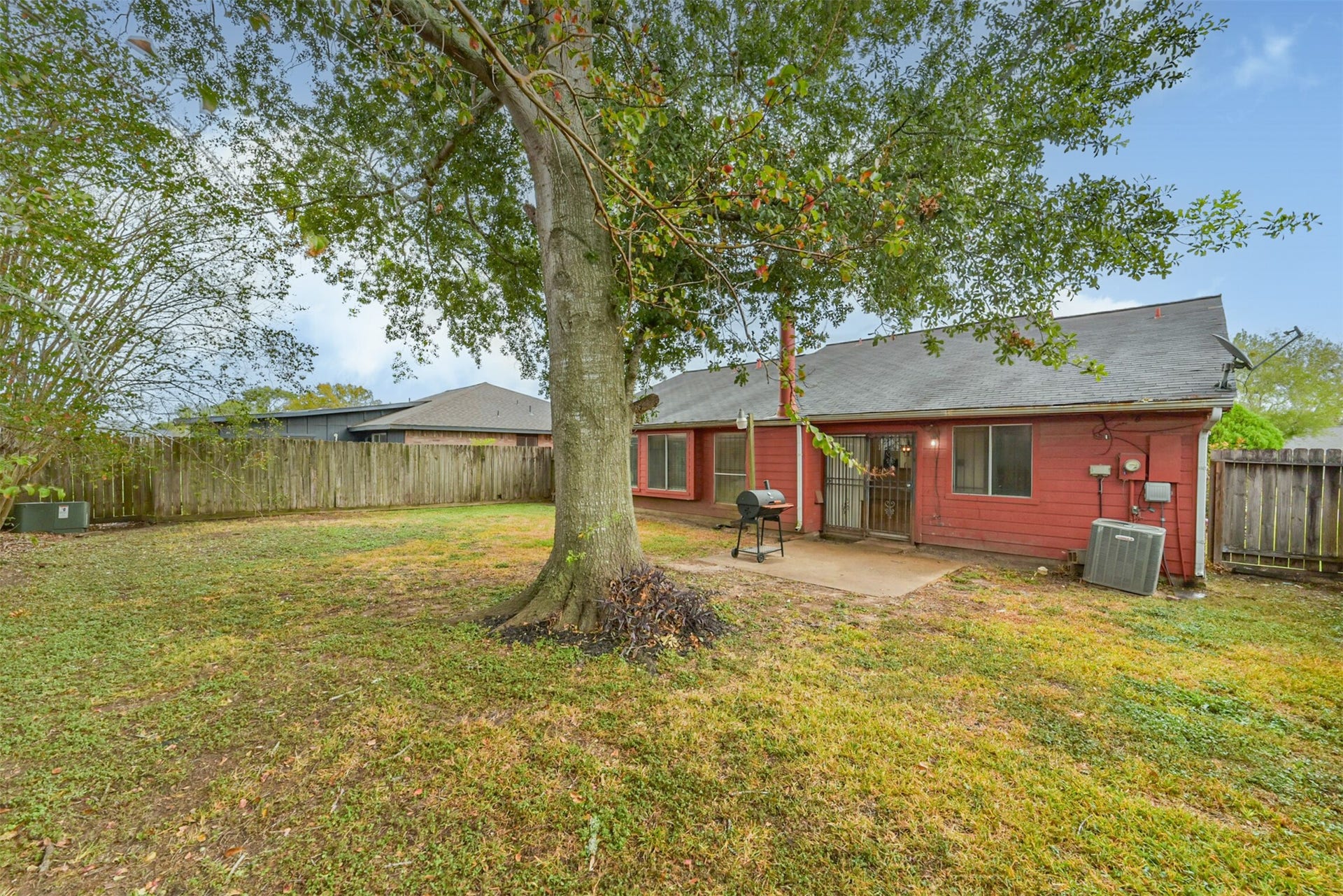 16510 Quiet Quail Drive, Houston, TX 77489 Spacious backyard with a large tree providing shade, a patio perfect for outdoor dining, and a wooden fence for privacy.