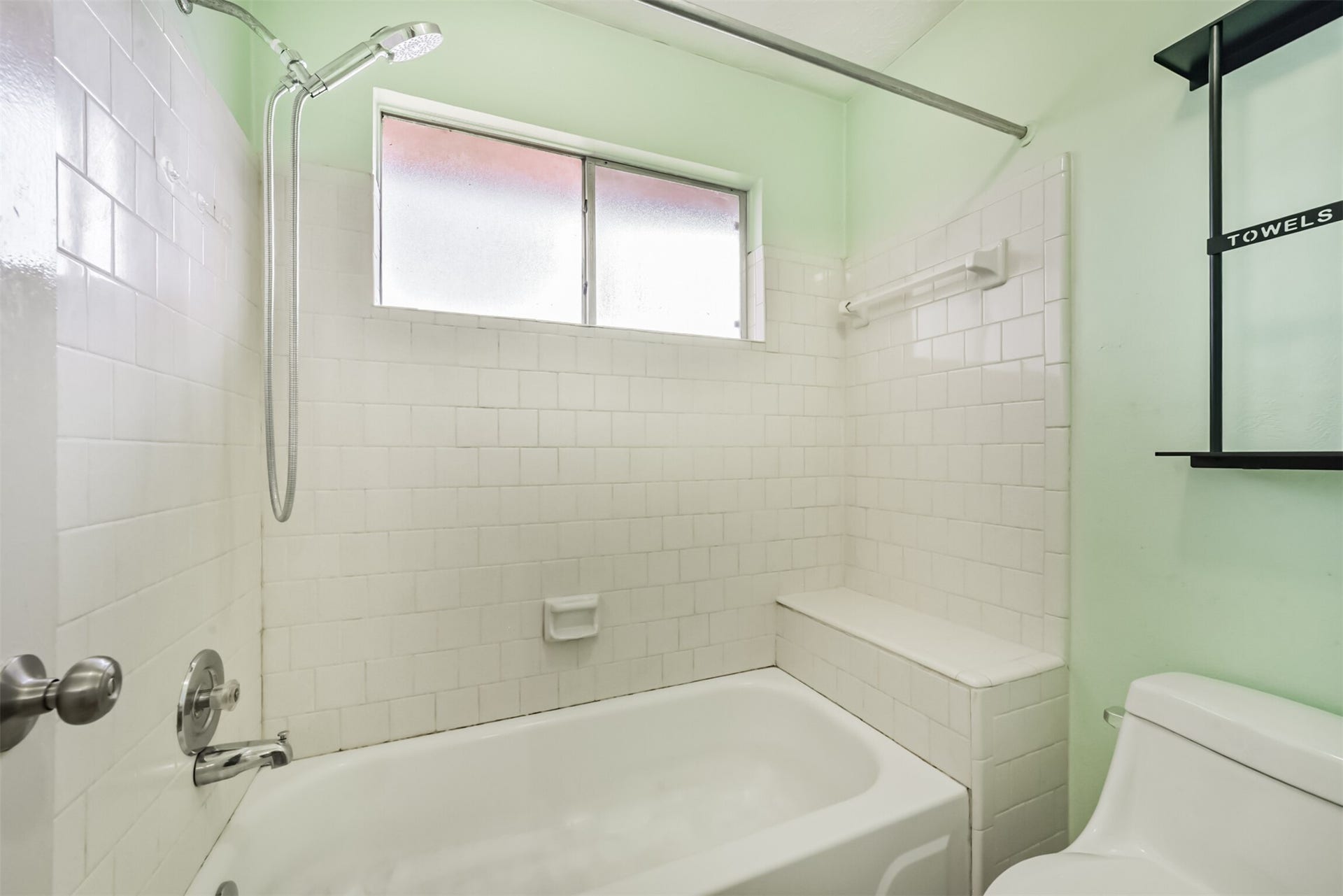 16510 Quiet Quail Drive, Houston, TX 77489 Bright and airy bathroom featuring classic white tiles, a built-in bathtub, and a convenient showerhead, complemented by natural light from the frosted window.