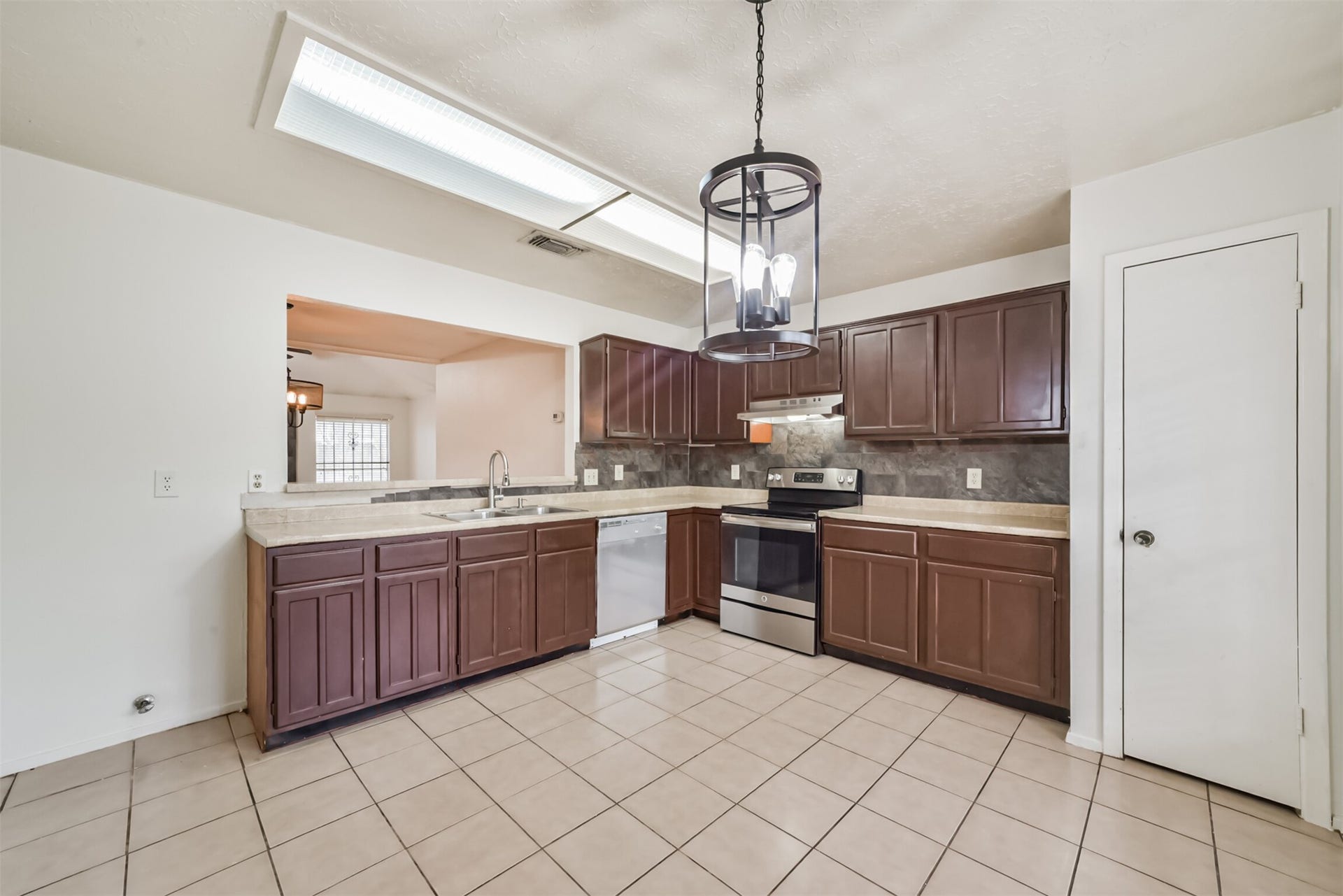 16510 Quiet Quail Drive, Houston, TX 77489 Spacious kitchen featuring dark wood cabinetry, modern stainless steel appliances, and ample counter space, accented by a stylish overhead light fixture.
