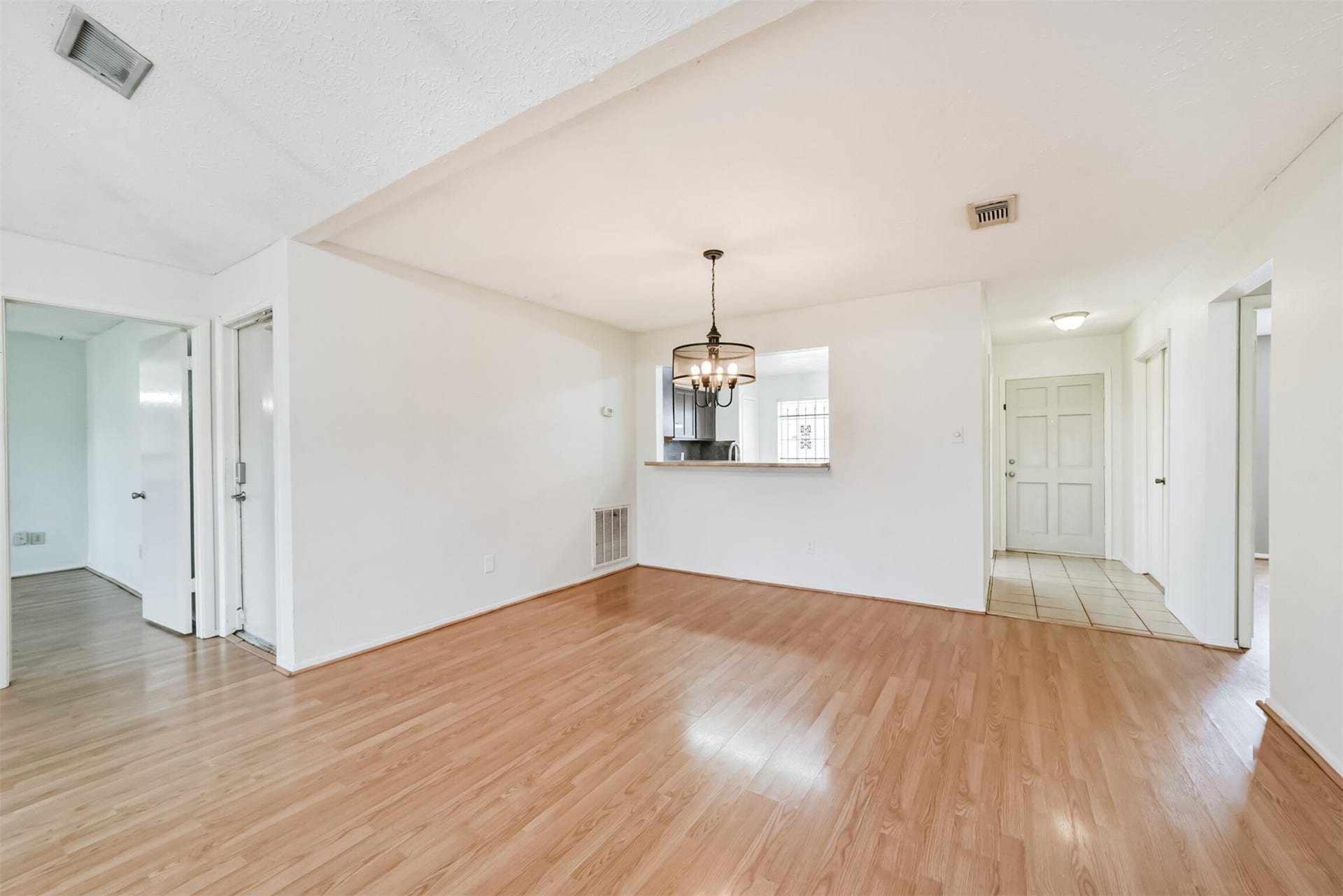 16510 Quiet Quail Drive, Houston, TX 77489 Spacious, light-filled living area with wood flooring, an elegant chandelier, and an open layout leading to the kitchen, creating a welcoming atmosphere.